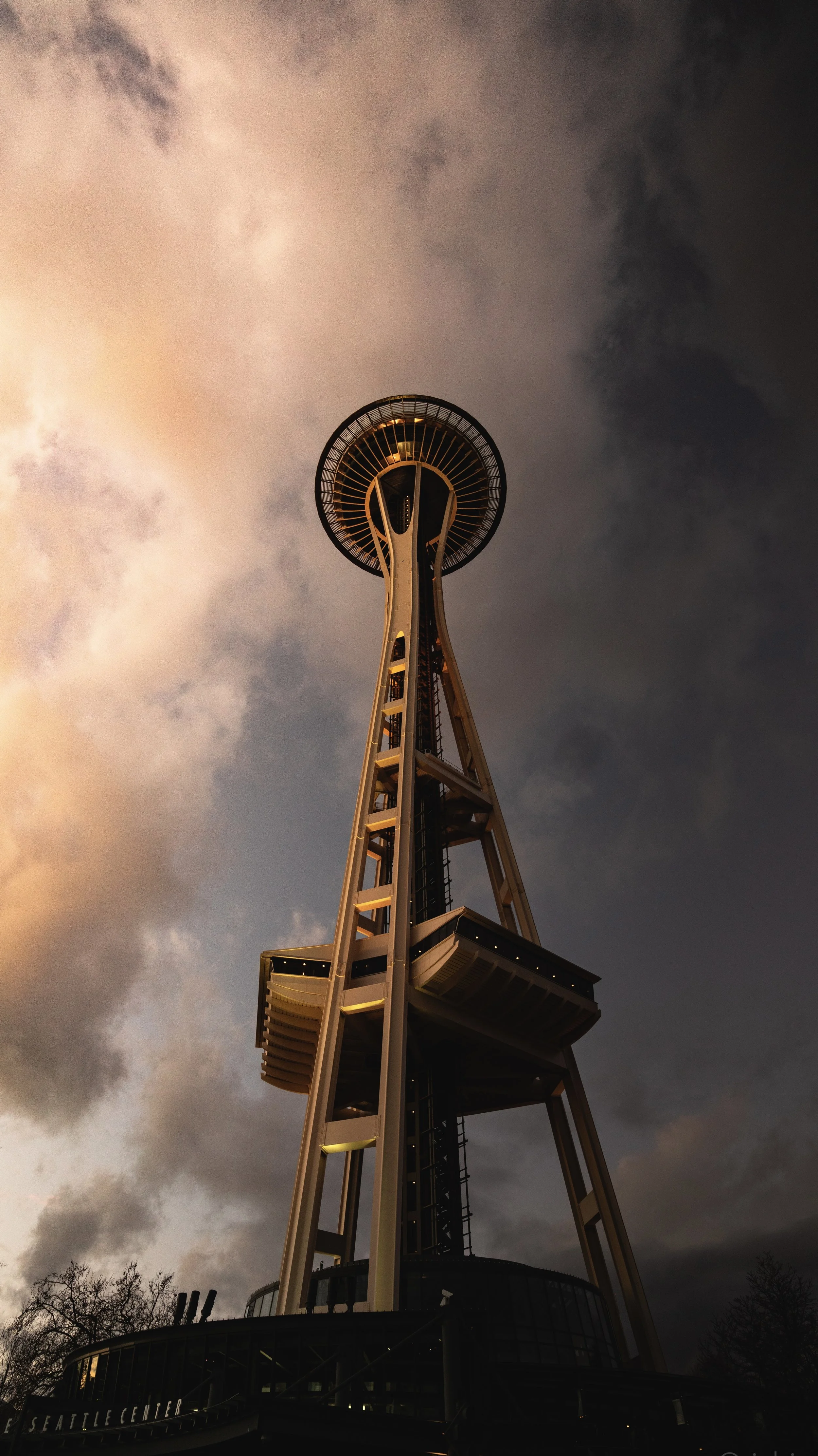 The Space Needle, a tall observation tower with a circular viewing platform at the top, against a cloudy sky during sunset.