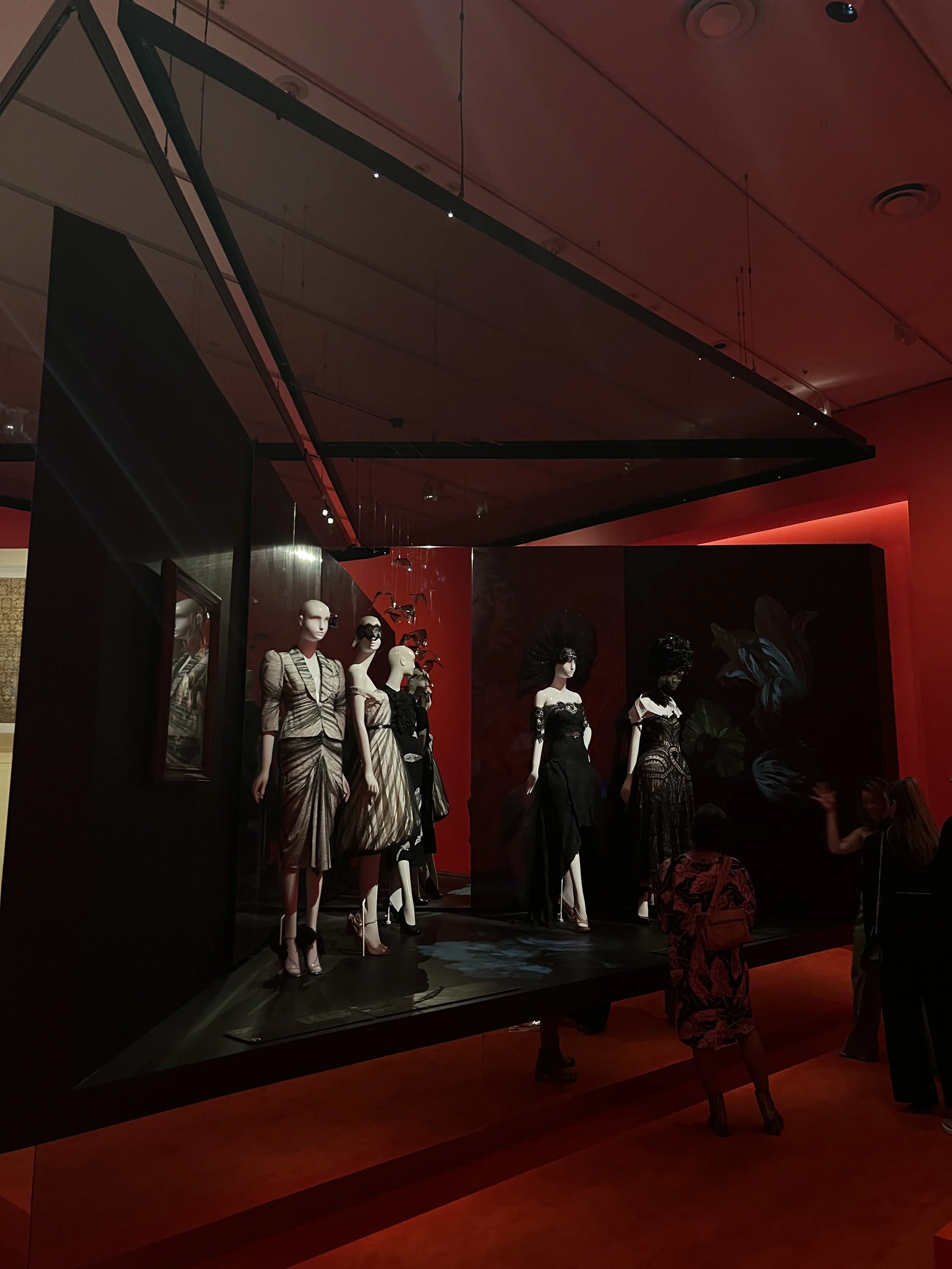Luxury fashion exhibition with black and gold couture under red lighting - visual identity inspiration for By T's luxury personal branding and reputation design in Perth