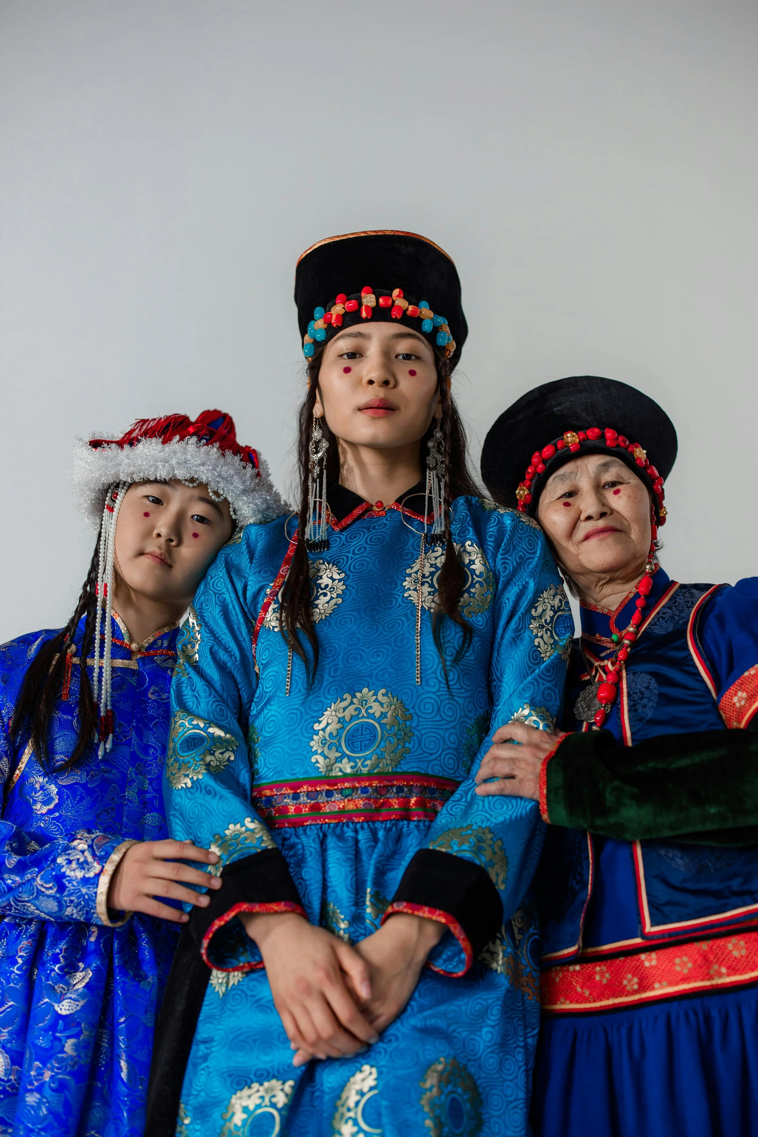Three generations of women wearing traditional dress, highlighting intergenerational cultural identity, heritage textiles, craftsmanship, and the continuity of dress traditions.