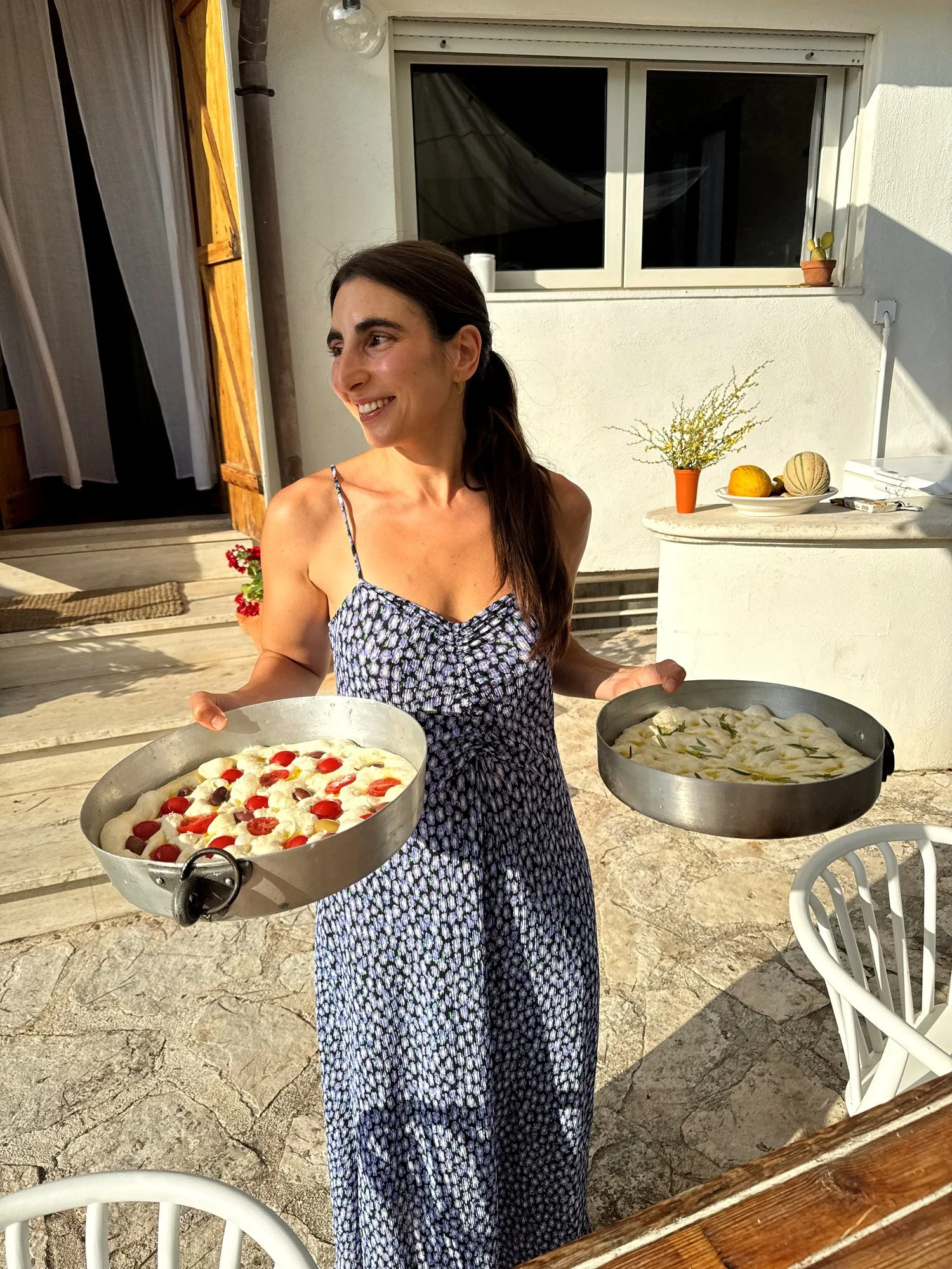 Gio trägt zwei Bleche mit Focaccia durch den Hof der Villa Patrizia