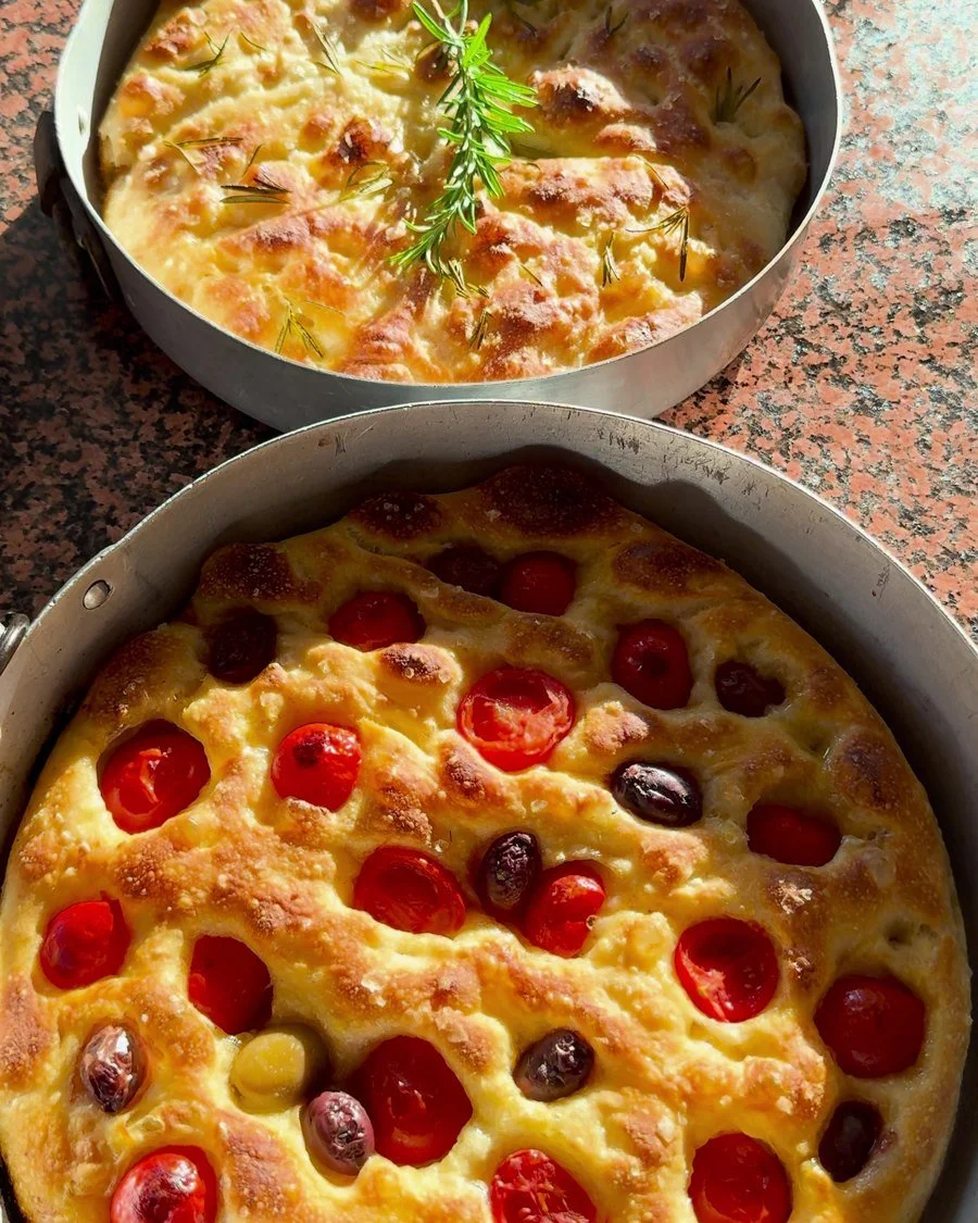 Zwei frisch gebackene Focacce mit Tomaten, Oliven und Rosmarin