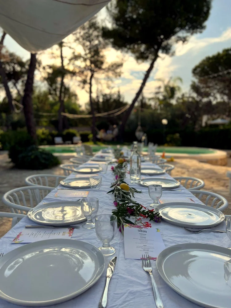 Gedeckte Tafel mit Blumen in der Abendstimmung, im Hintergrund der Pool