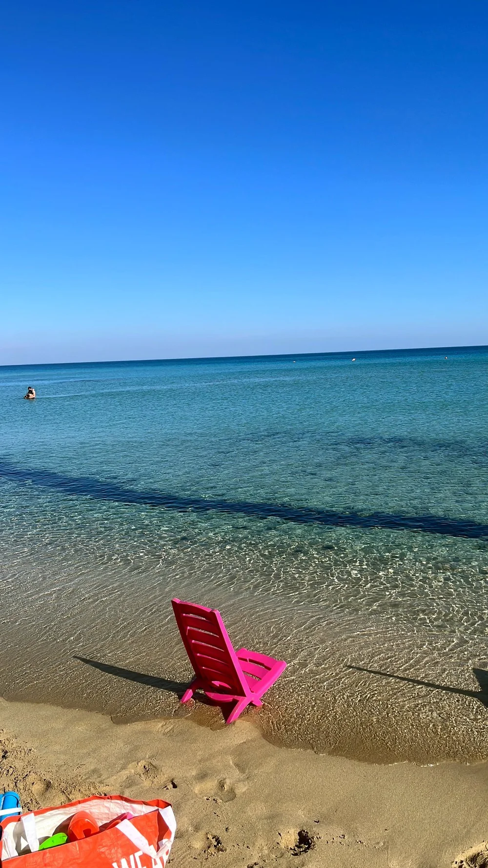 Pinker Strandstuhl im flachen Wasser, Salento im Mai