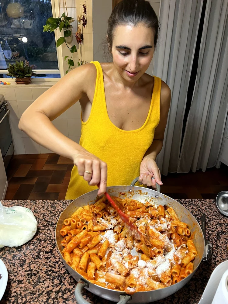 Gio rührt Parmesan unter Rigatoni in einer großen Pfanne