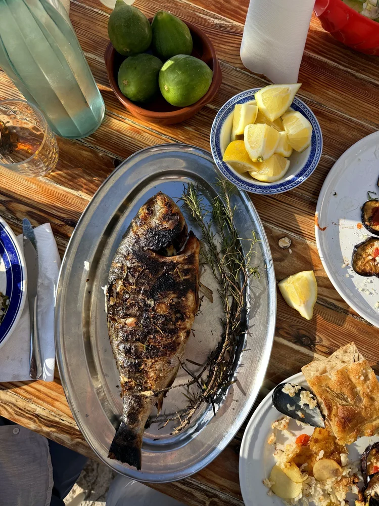 Gegrillte Dorade auf einer Platte am gedeckten Tisch