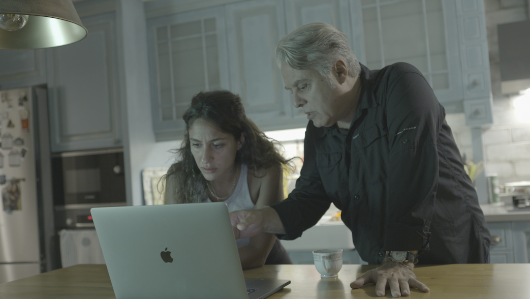A man and woman looking at a laptop on a kitchen counter, appearing concerned.
