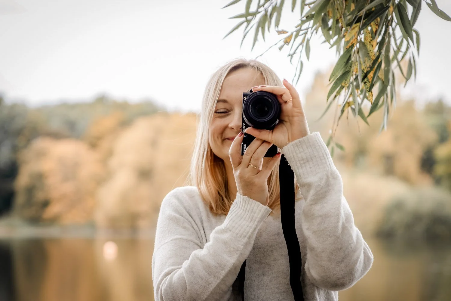 Eine junge Frau macht ein Foto mit einer Kamera an einem Herbsttag in einer natürlichen Umgebung.