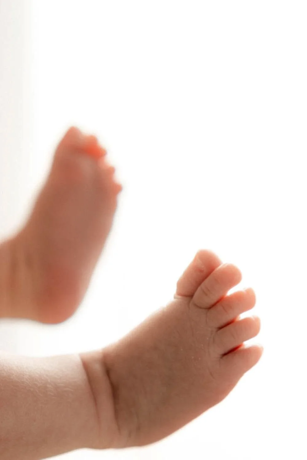 Nahaufnahme einer Babyhand mit kleinen Fingern, vor hellem, gleichmäßig beleuchtetem Hintergrund.