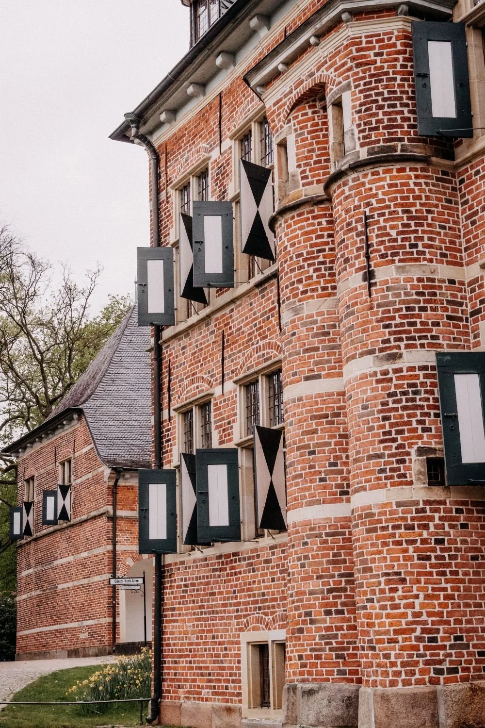 Historisches rotes Backsteingebäude mit offenen schwarzen und weißen Fensterläden