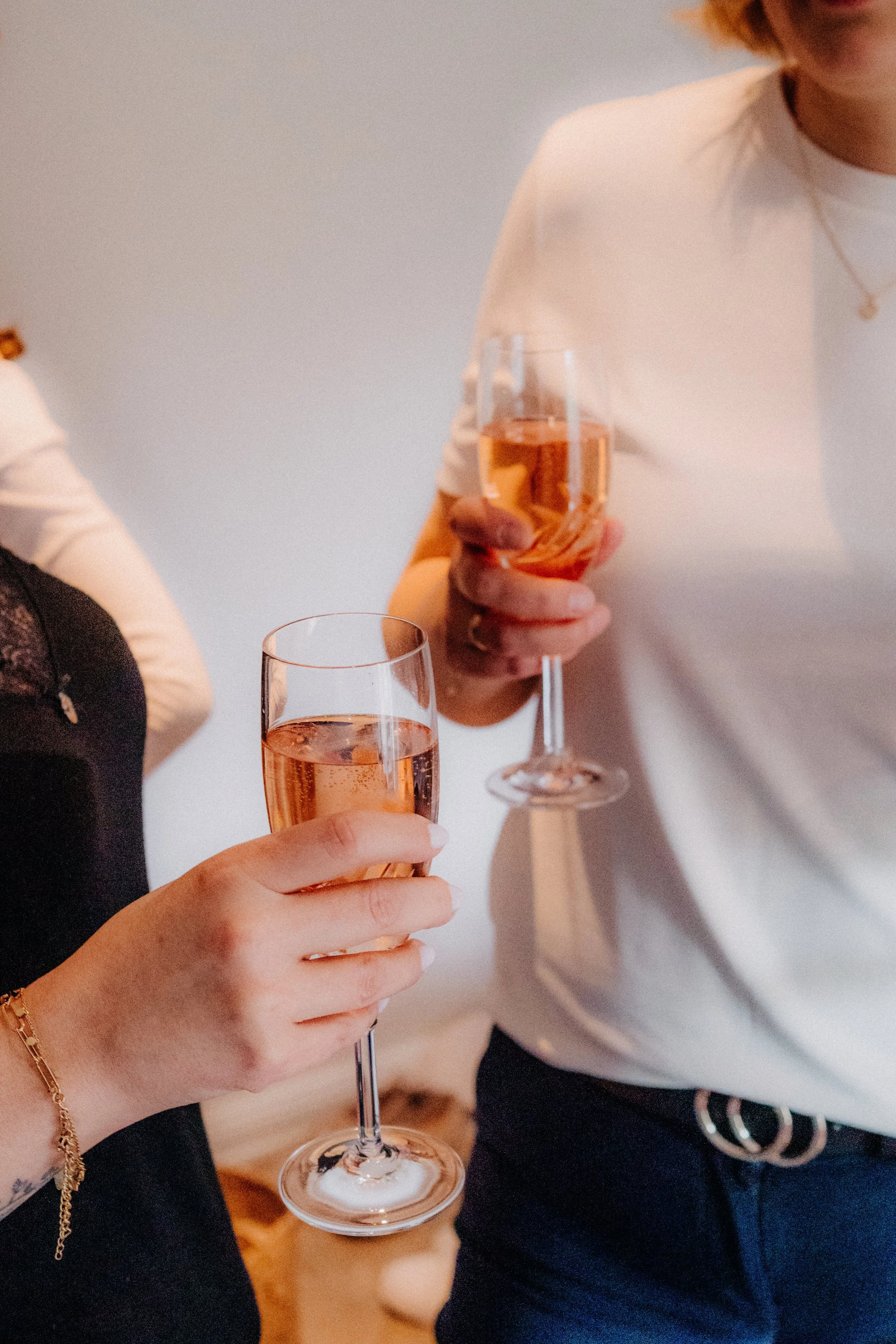 Zwei Frauen stoßen mit Gläsern Rosé-Sekt an.