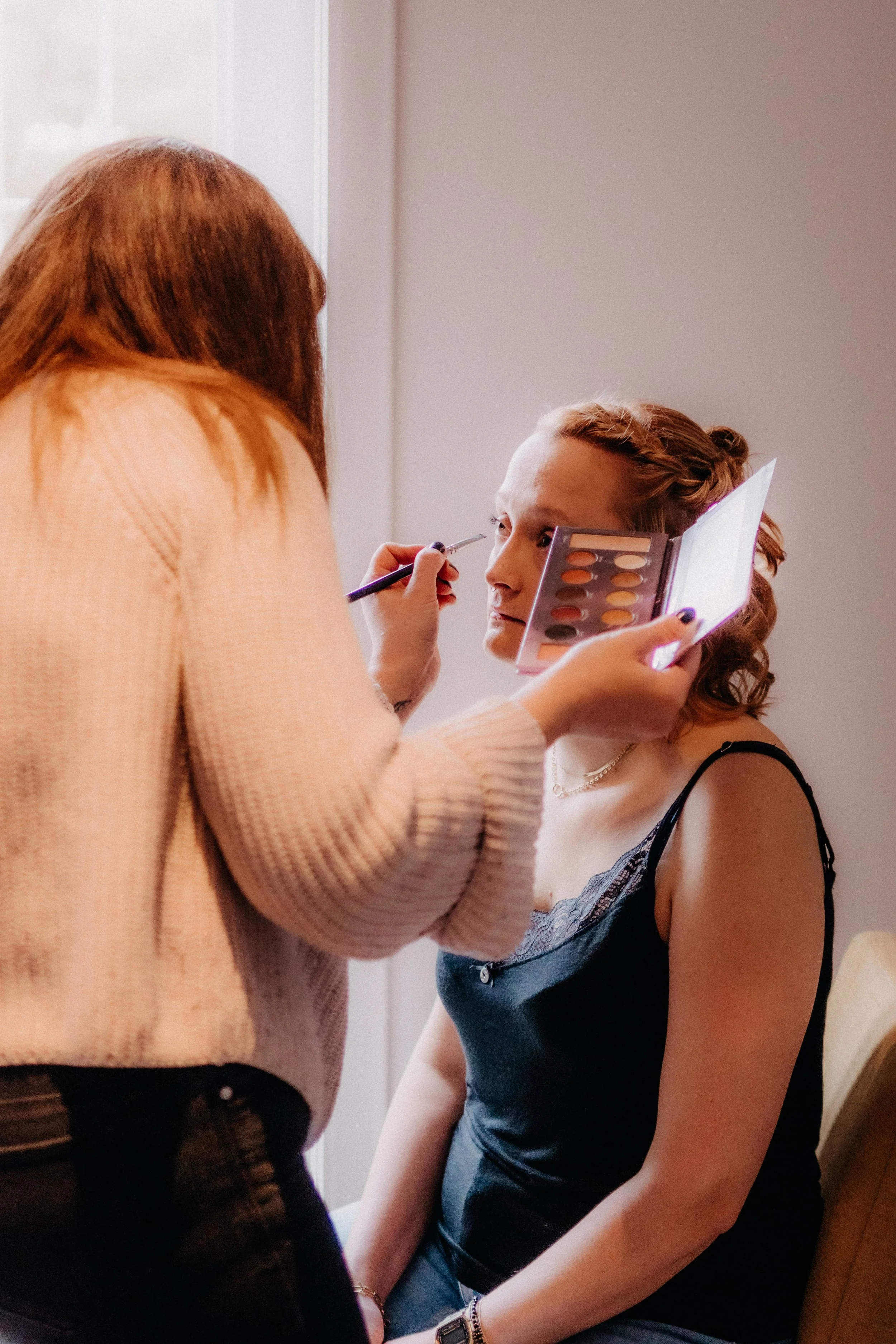 Frau mit roten Haaren bekommt Make-up von einem Make-up-Artist