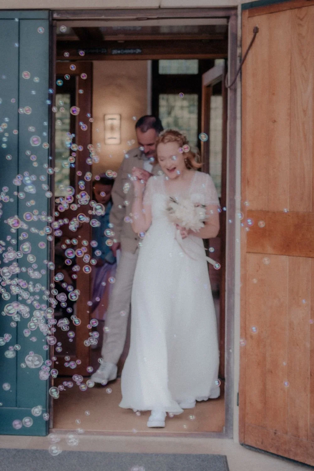 Ein Brautpaar, das glücklich bei ihrer Hochzeit im Freien entgegeneilt, umgeben von Seifenblasen.