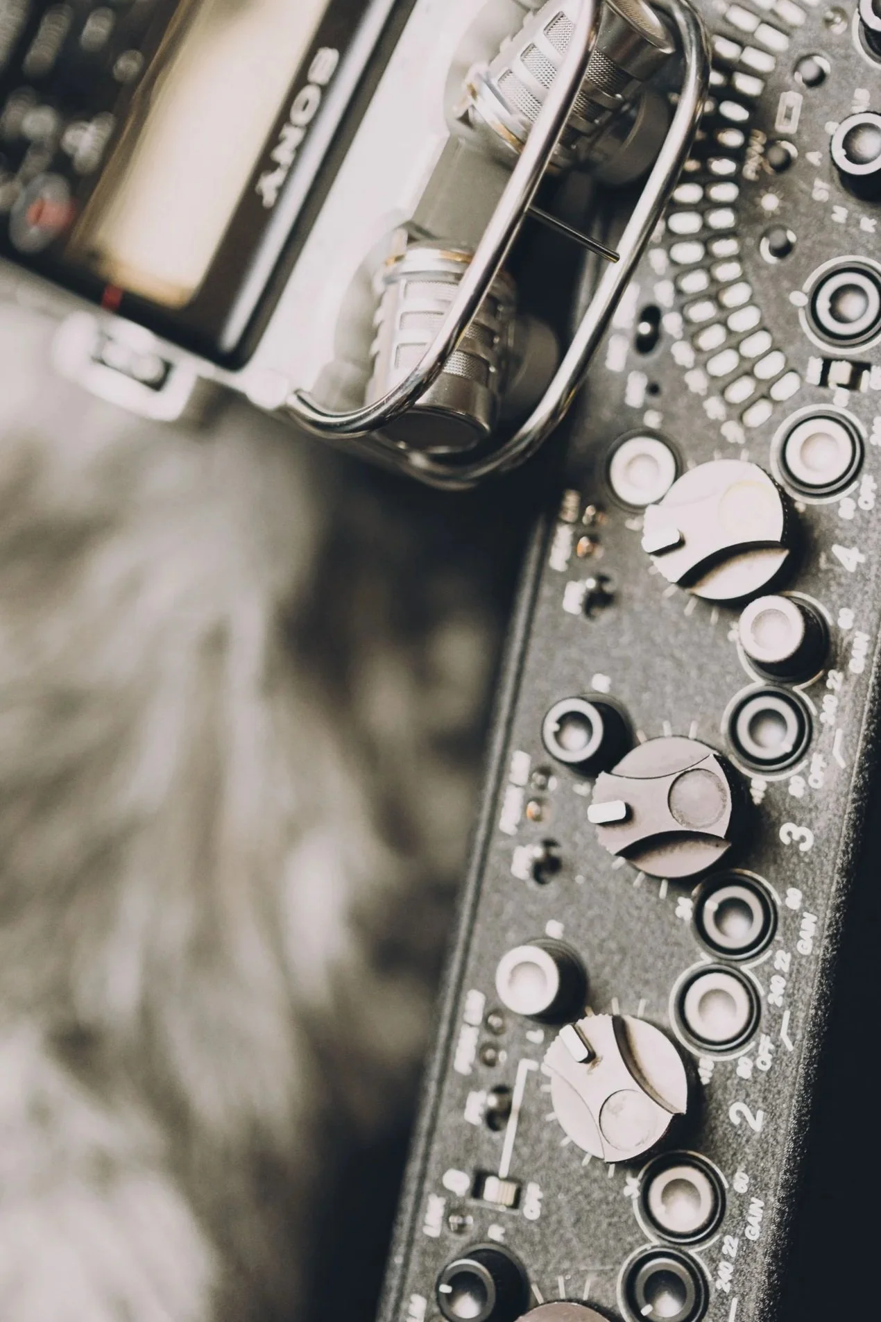 Close-up of a DJ mixer with several knobs and dials, and a wire basket holding an audio cable.