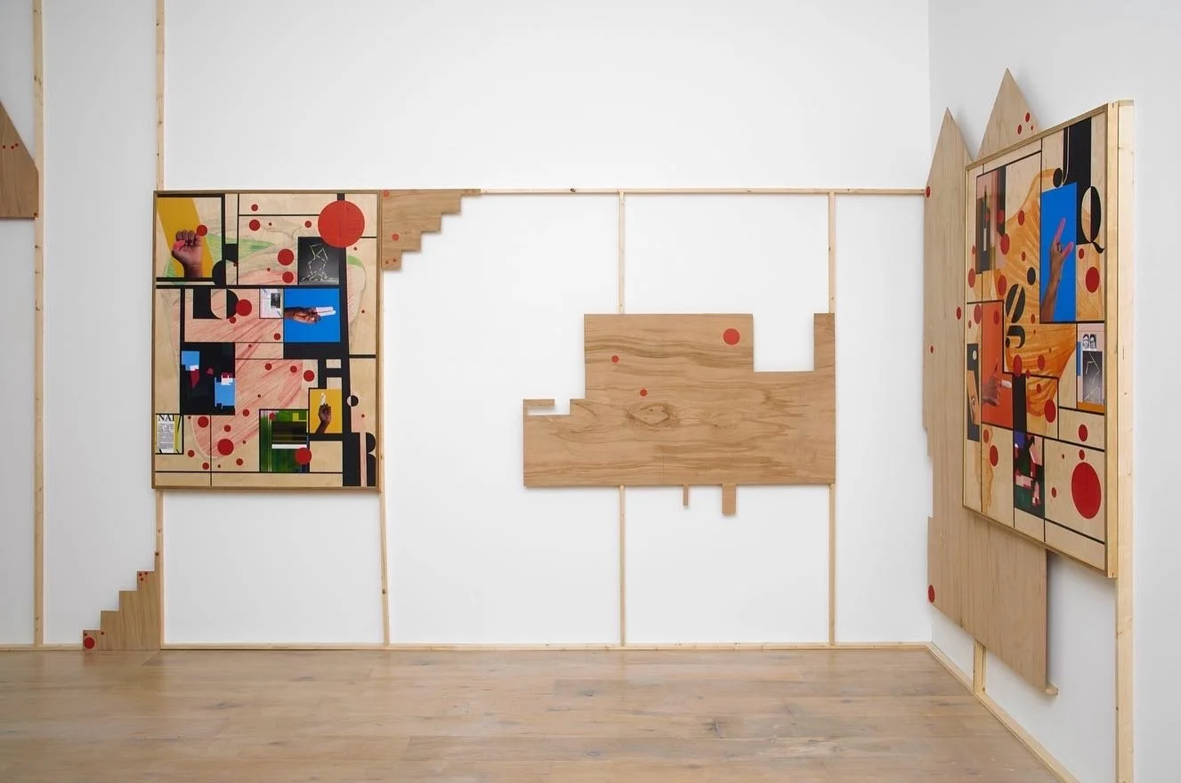An art installation on a white wall with wooden frames, colorful abstract images, and red circular accents.