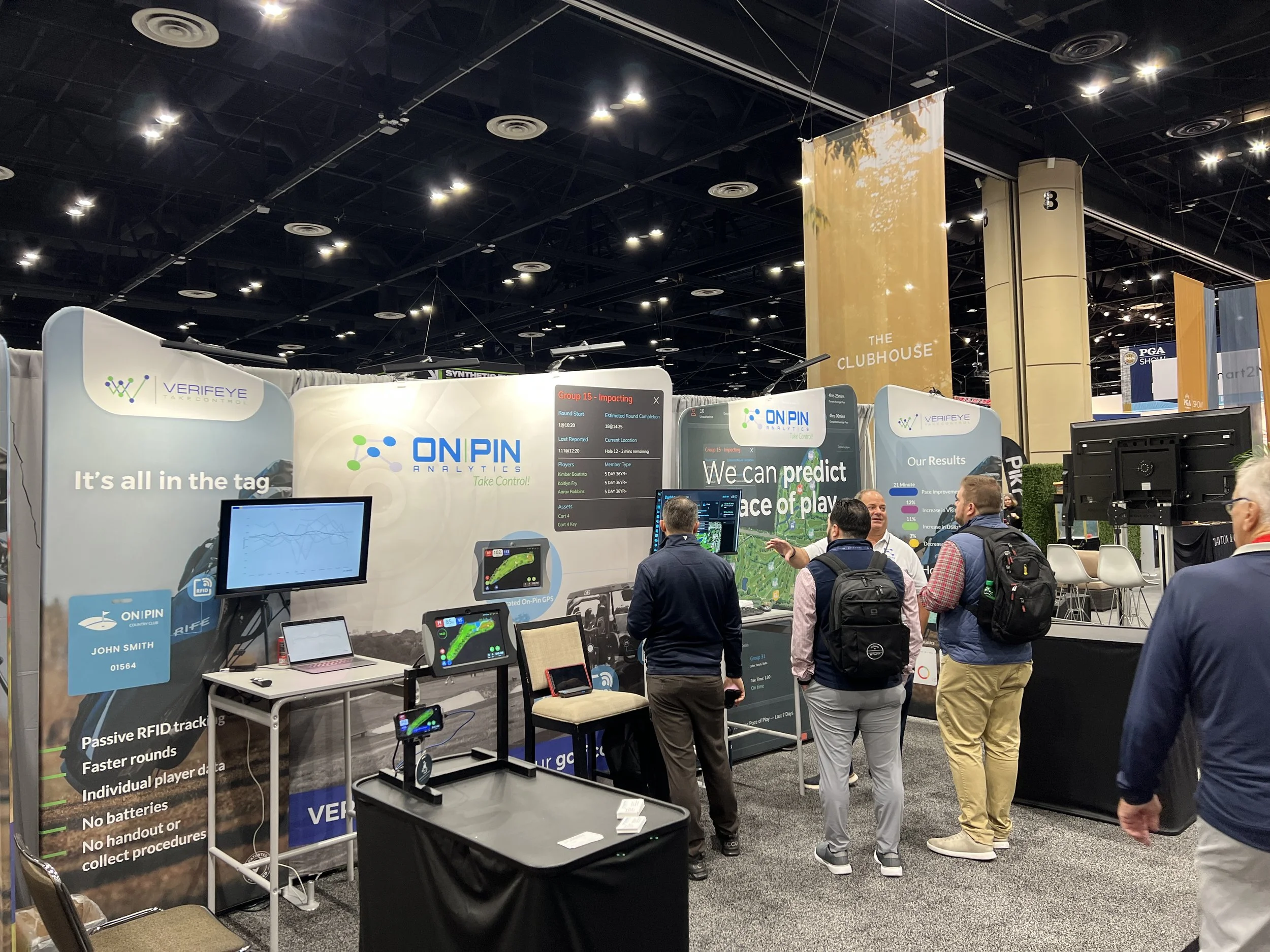 Trade show booth for ON PIN ANALYTICS featuring screens, banners, and people engaging in discussion about RFID tracking technology.