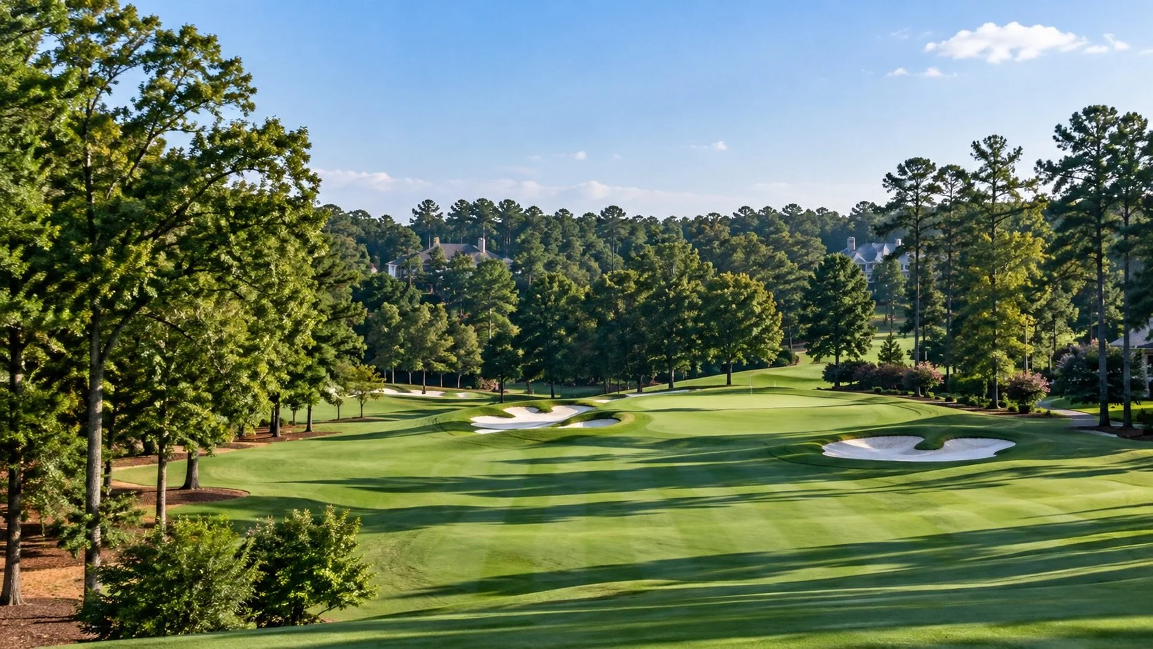 Striped golf fairway leading to a green with sand bunkers, lined with pine and hardwood trees and homes along the course, for golf communities in Cobb County, Georgia
