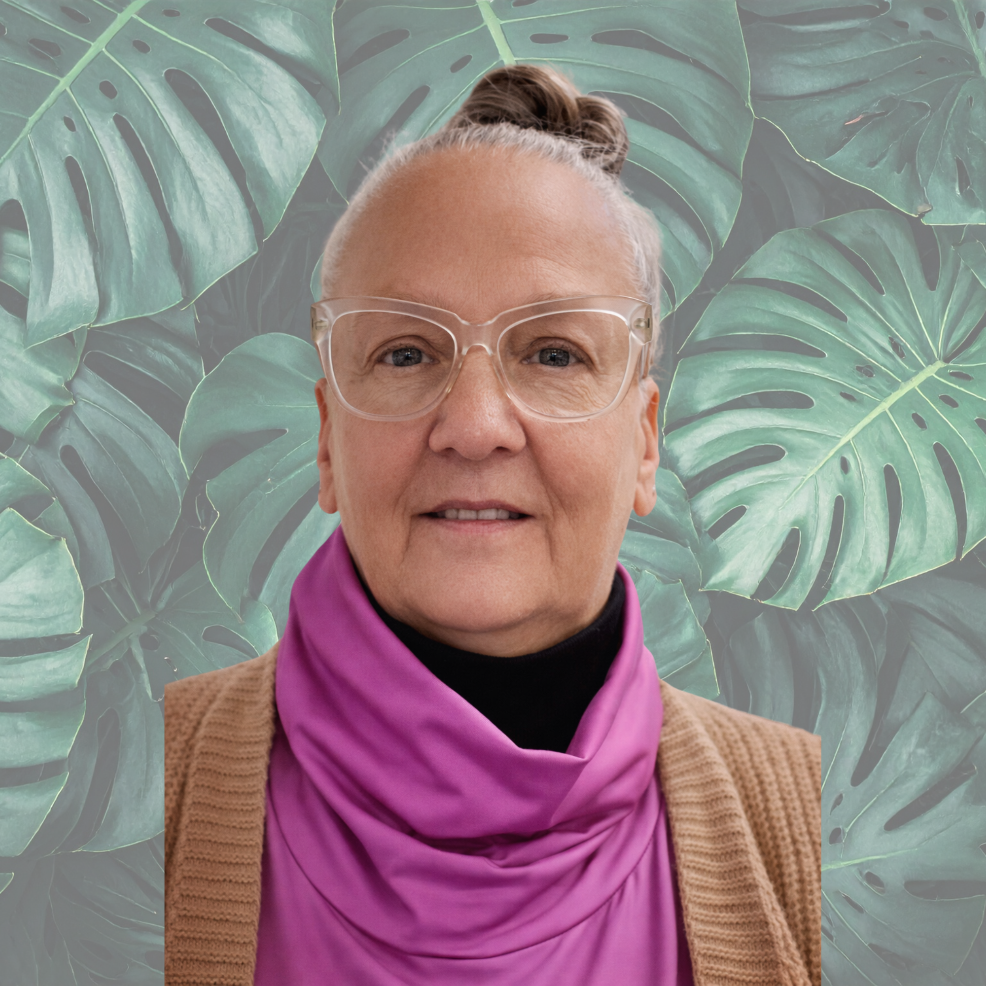 Close-up of an older woman with glasses, wearing a purple scarf and a beige cardigan, smiling at the camera.