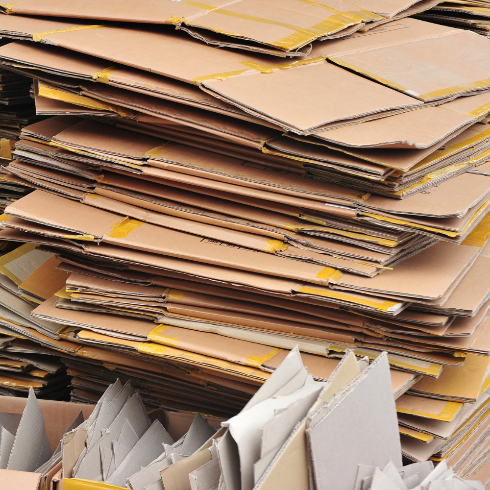 A large stack of flattened cardboard boxes with some taped edges.
