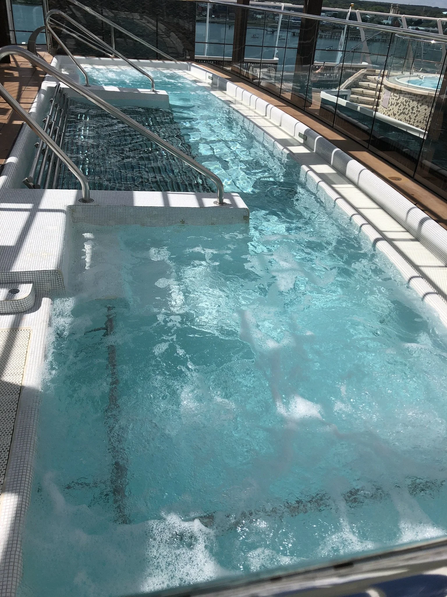 Indoor hot tub with multiple jets and seating, overlooking city skyline through glass walls.