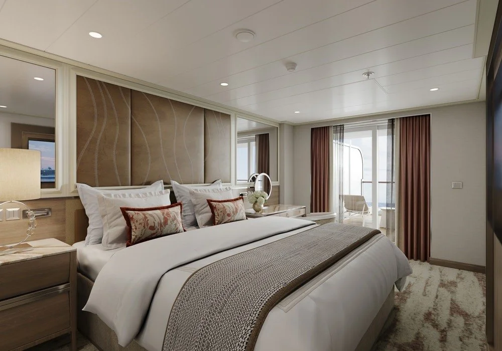 Modern bedroom with a large bed, decorative pillows, bedside tables, a small desk with a mirror, and a balcony with outdoor seating.
