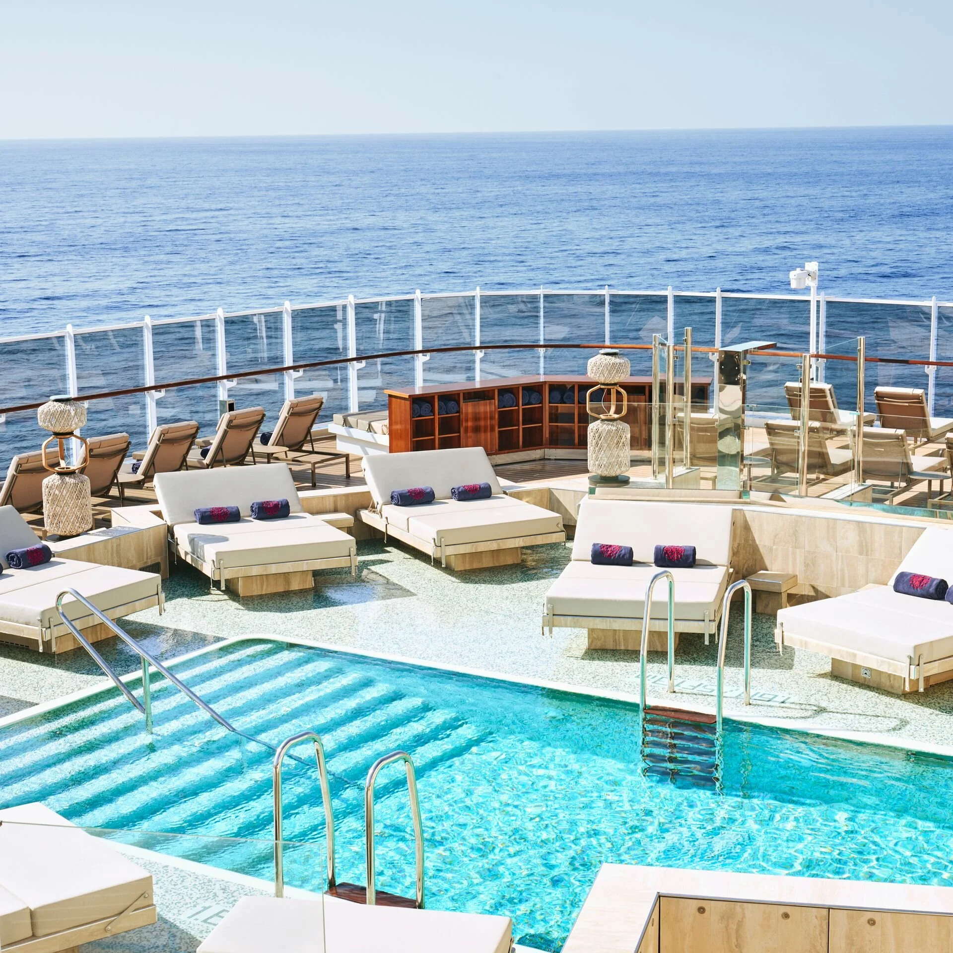 A pool on a luxury cruise ship surrounded by sun beds