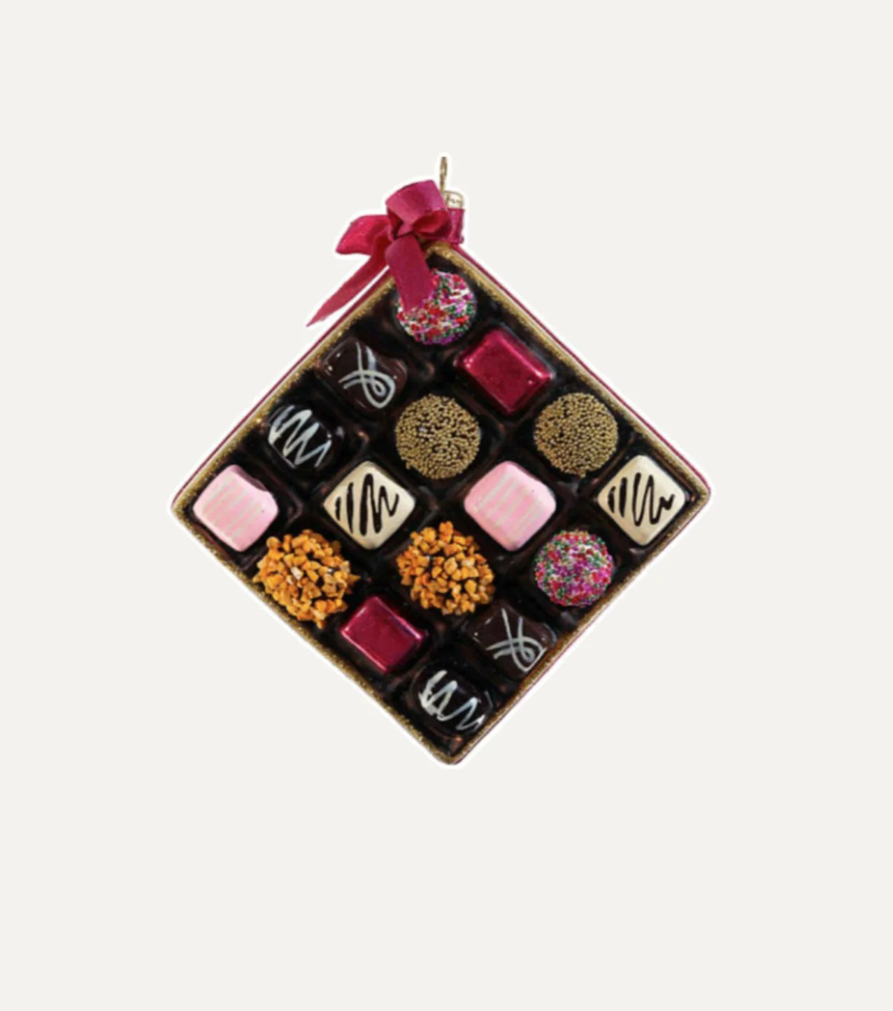 Box of assorted chocolates decorated with various toppings and drizzles, trapped inside a square box with a red ribbon on top.