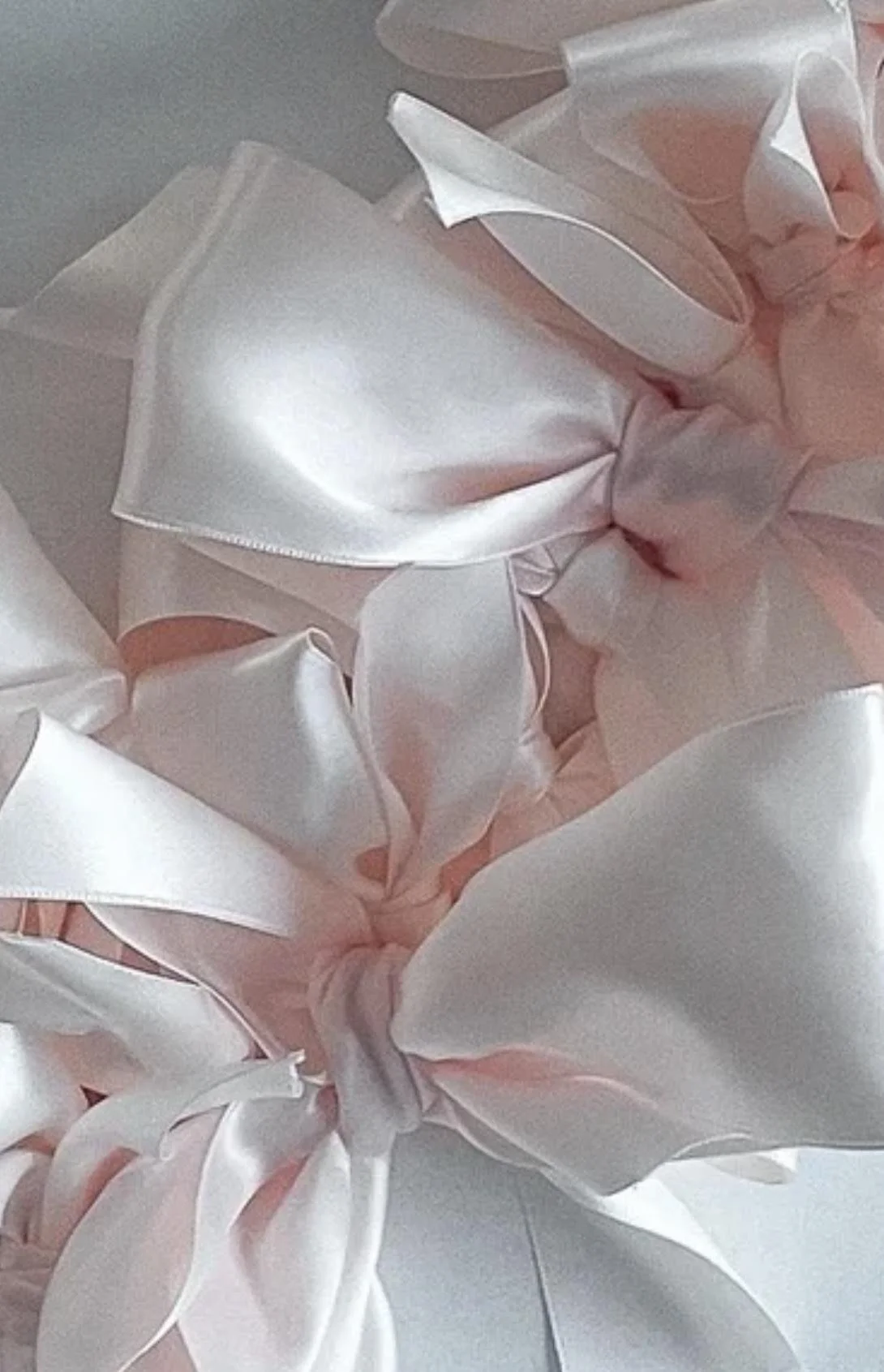 Close-up of a pink satin ribbon tied in a bow with large loops and tails.