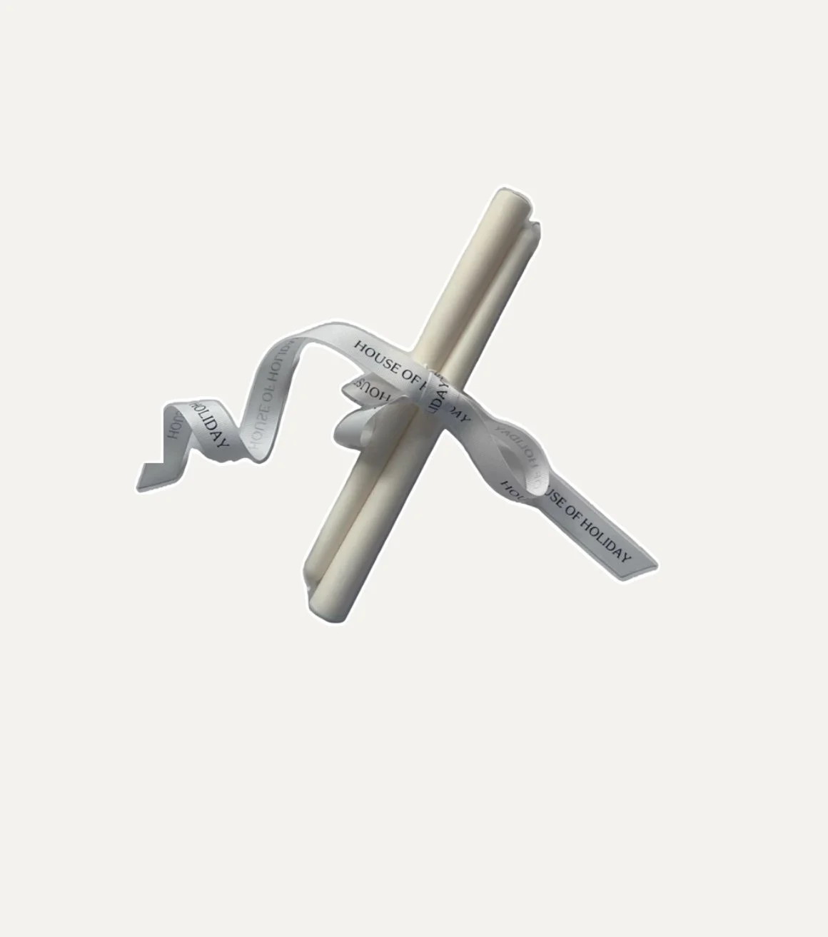 A paper straw with a tea bag tag attached, float in mid-air against a plain background.