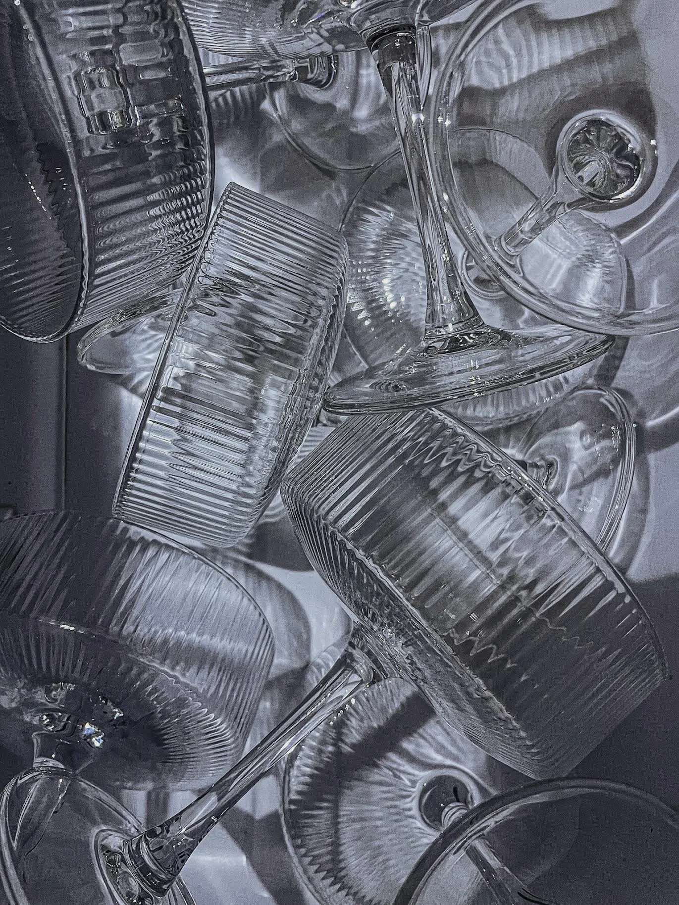 A collection of empty glassware, including wine glasses and tumblers, arranged on a reflective surface.