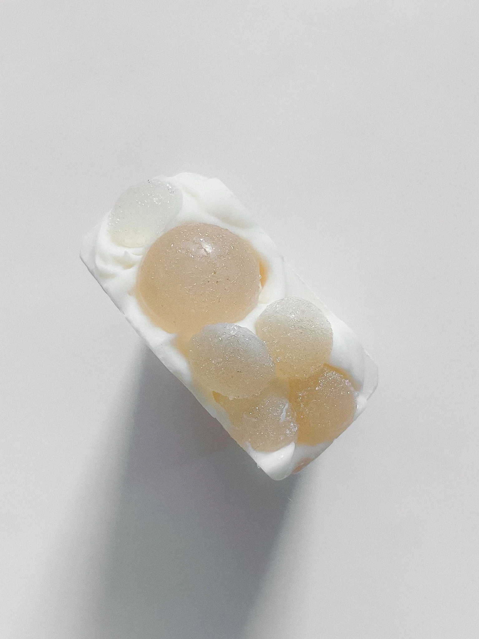 A rectangular block of white soap with embedded translucent spheres of varying sizes.