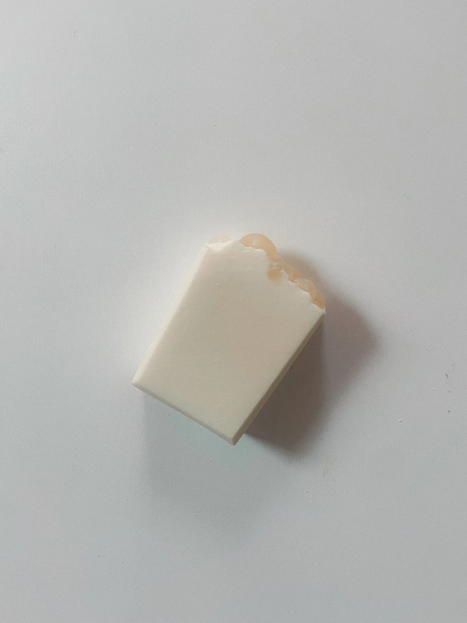 A partially eaten white chocolate bar with caramel inside on a white surface.