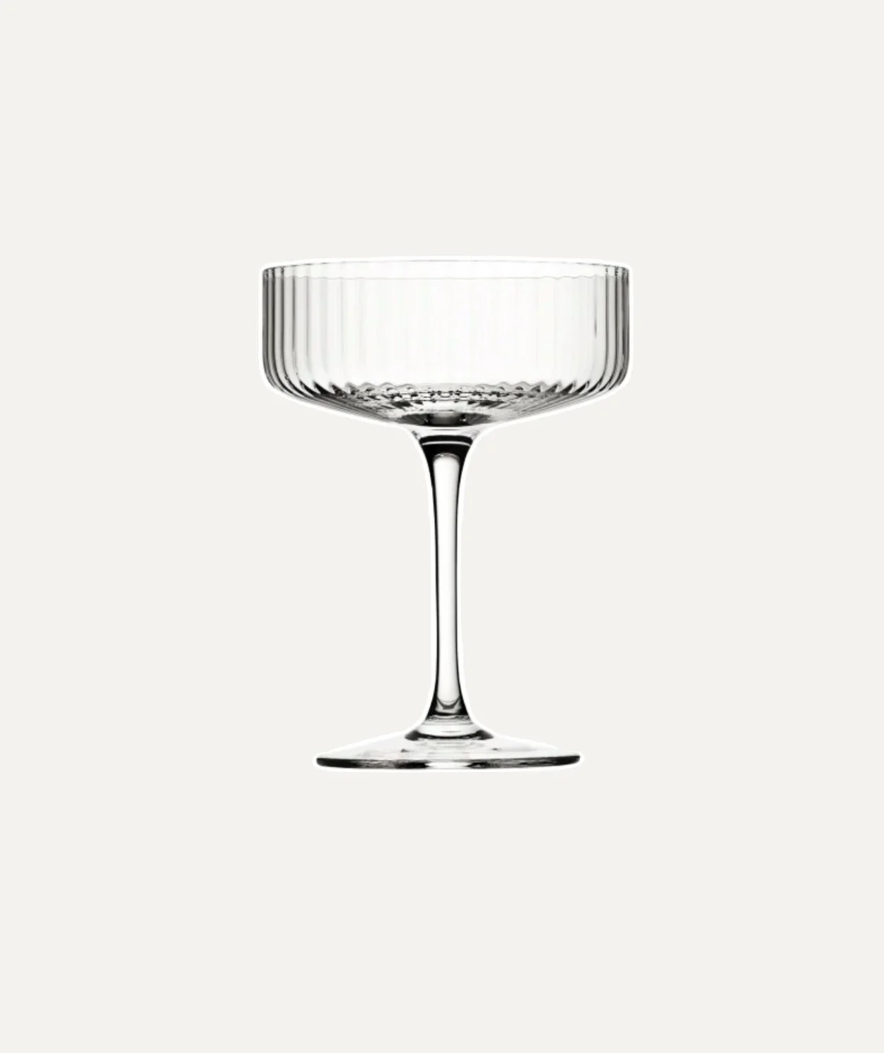 A clear, empty coupe cocktail glass with a ribbed design on the bowl, set against a plain light background.