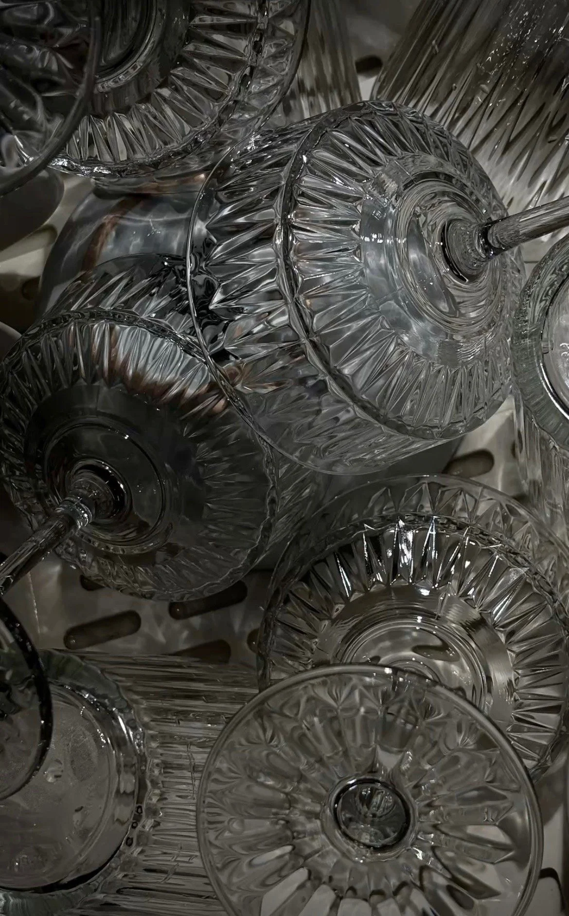 A collection of clear, decorative glass goblets and vases with intricate patterns, arranged closely together.