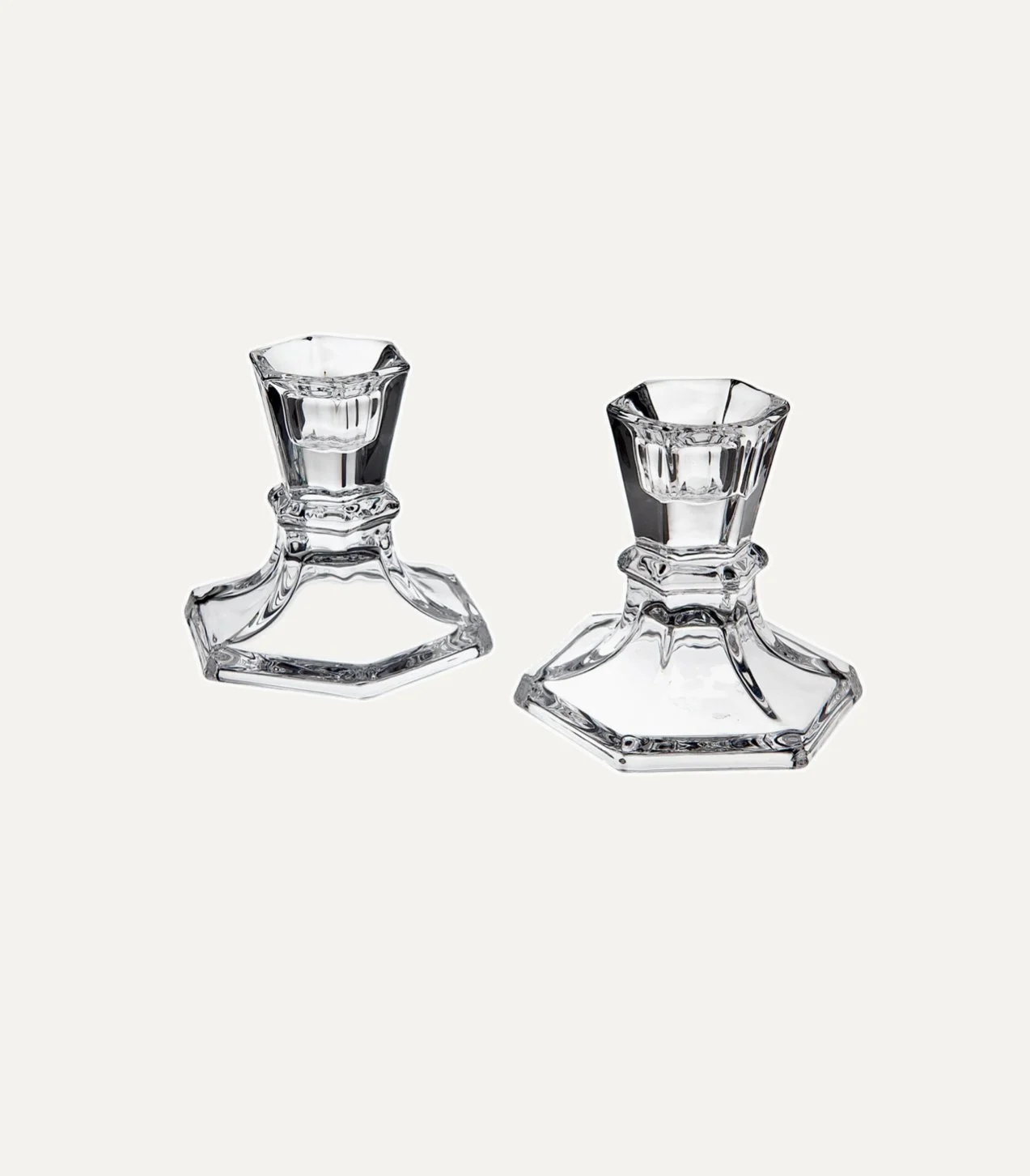 Two clear glass candle holders on a plain background.