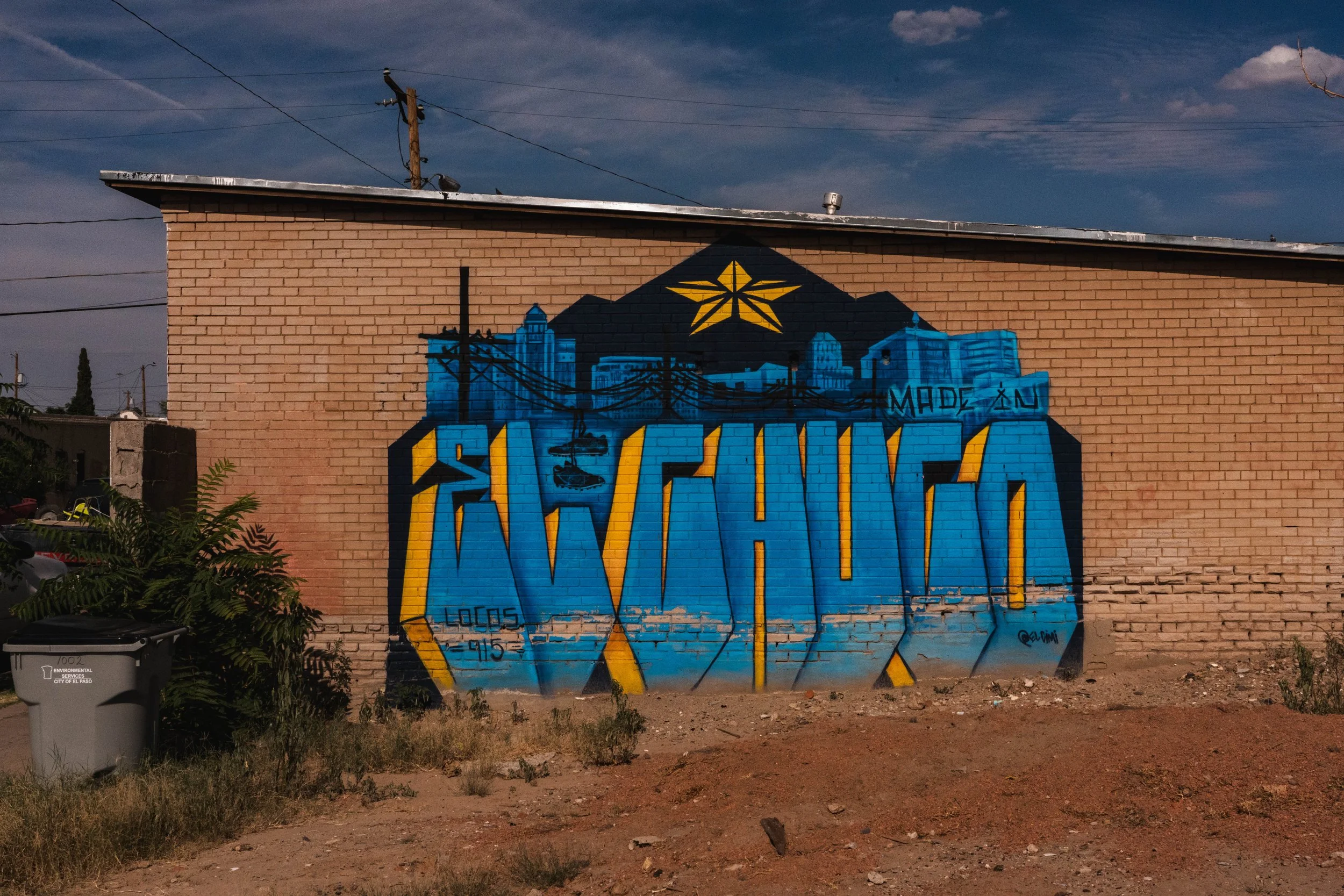 Graffiti on a brick wall featuring a colorful cityscape with mountains and a star, with the word 'ALBUQUERQUE' in stylized blue and yellow letters, with 'Made in' and 'Lopez 915' written nearby.