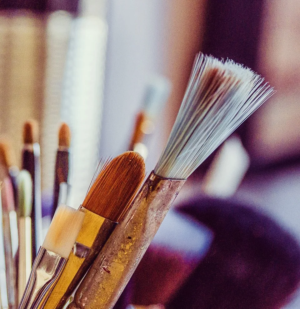Close-up of painting brushes with various sizes and shapes, stored upright.