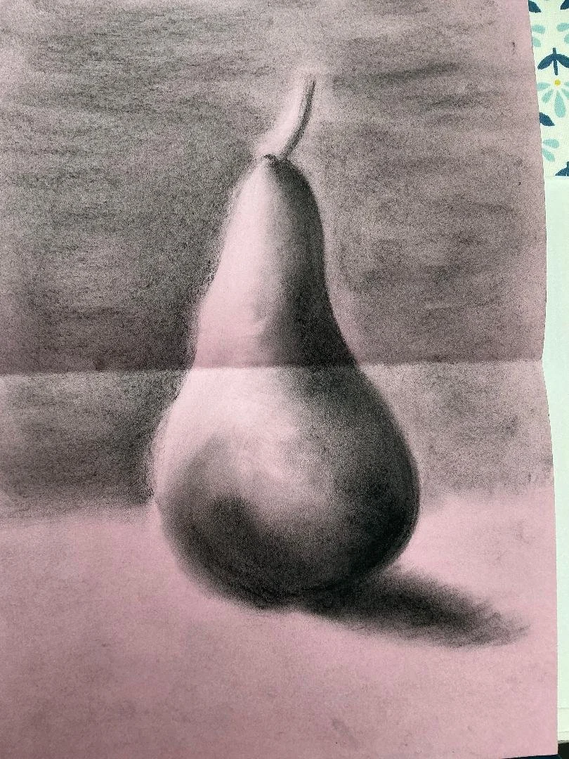 A black and white photograph of a pear resting on a table with a shadow cast beside it.