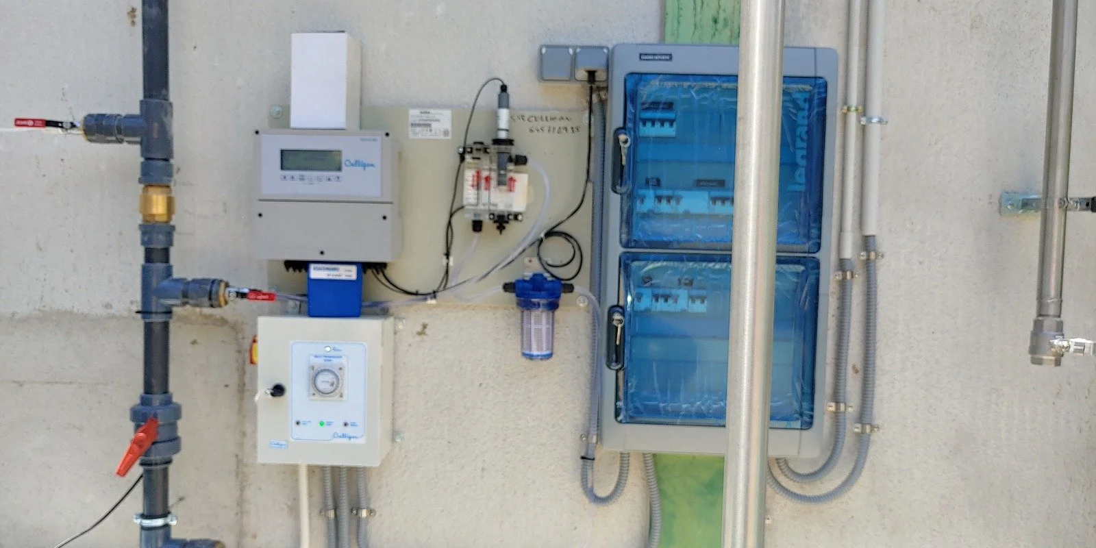 Panel de control y filtros de un sistema de agua en una pared exterior.