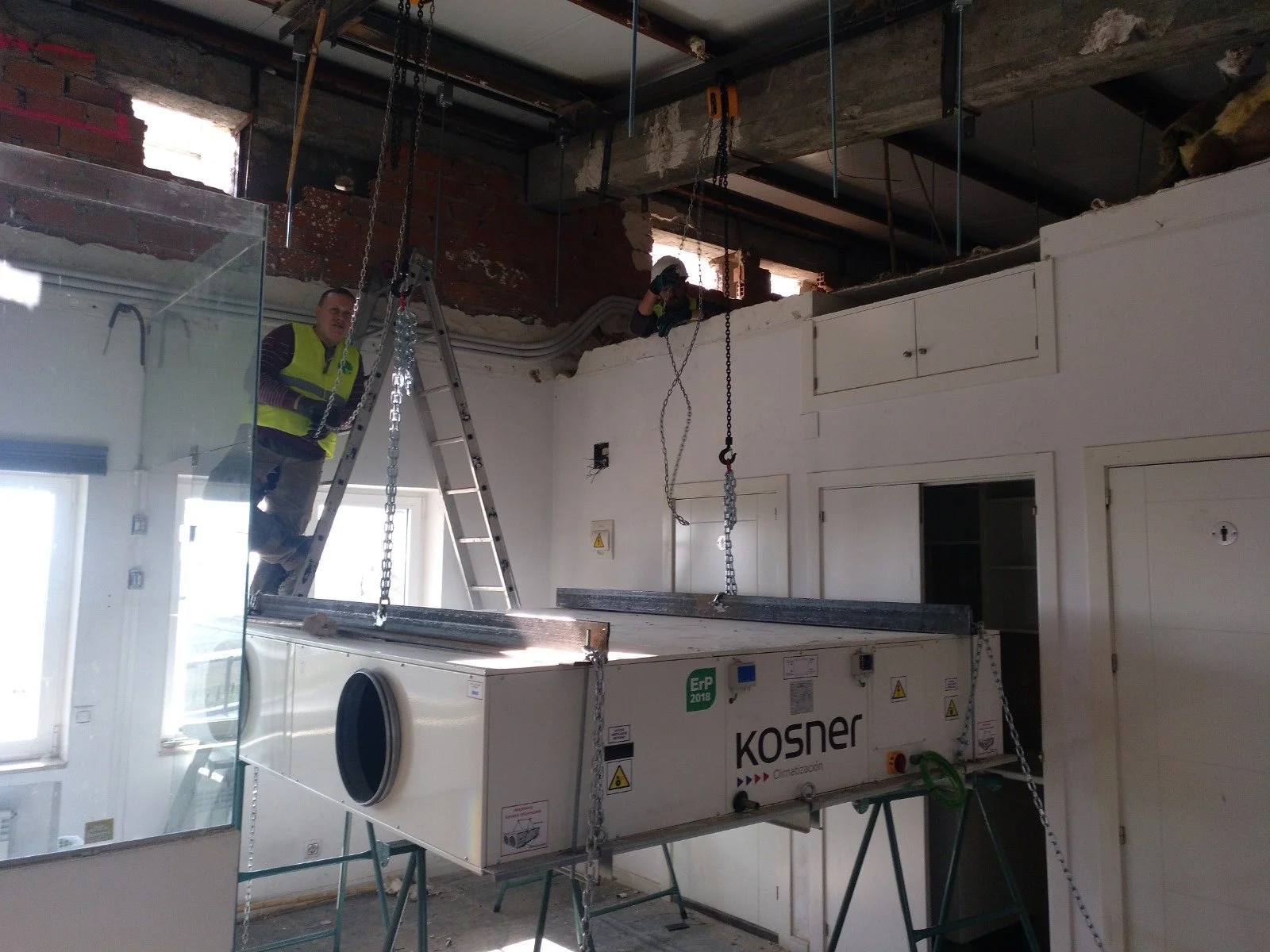 Trabajadores instalando un sistema de aire acondicionado en una habitación en construcción o renovación.
