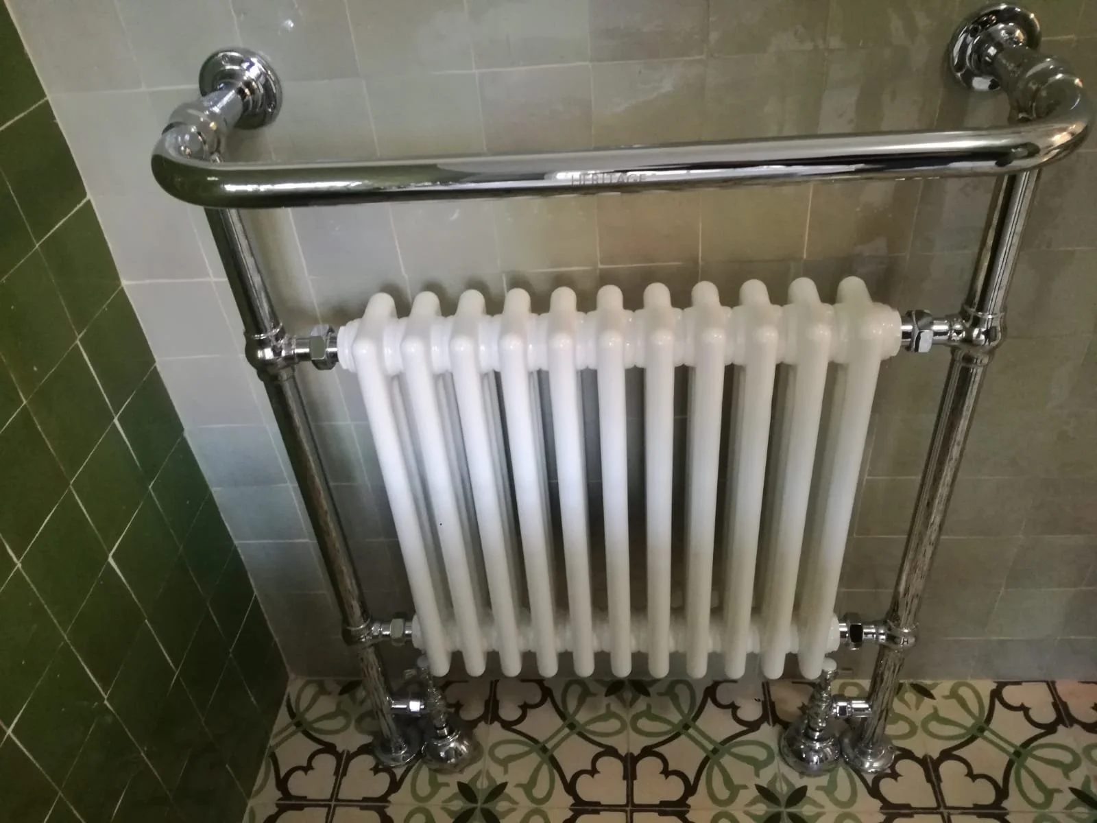 Calefactor vertical con espeques de cerámica reflectante, instalado en una pared de azulejos en un baño.