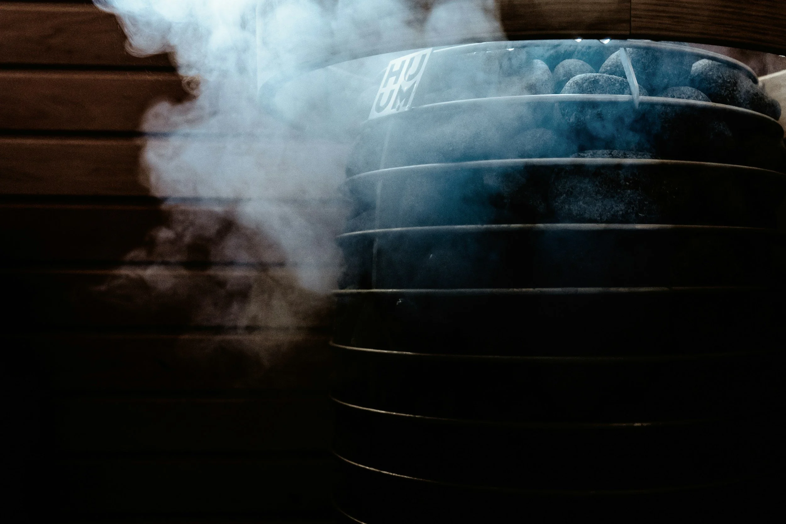 Stacked steamers with smoke or steam rising on a dark background, with a wooden wall behind them.