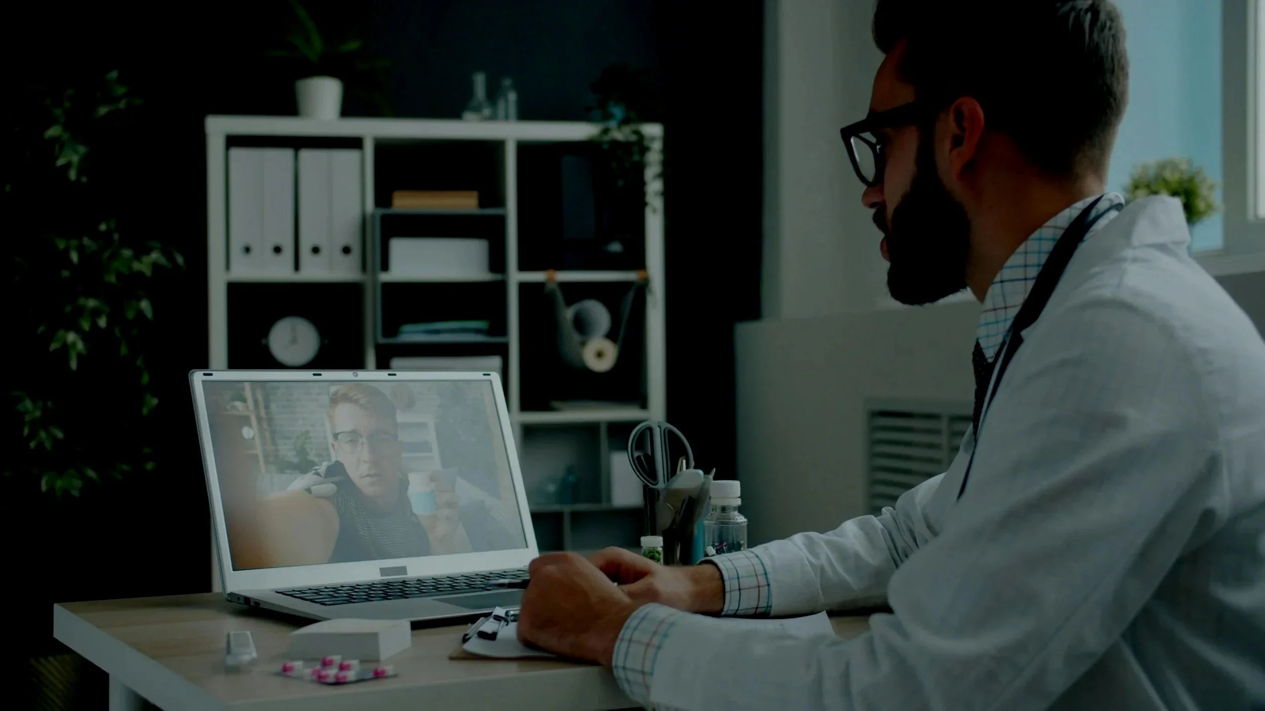 A person is donating blood, with a healthcare worker preparing to draw blood from their arm. The healthcare worker is wearing gloves, and the patient's arm has a bandage around the puncture site. Medical supplies and equipment are visible on a table in the background.