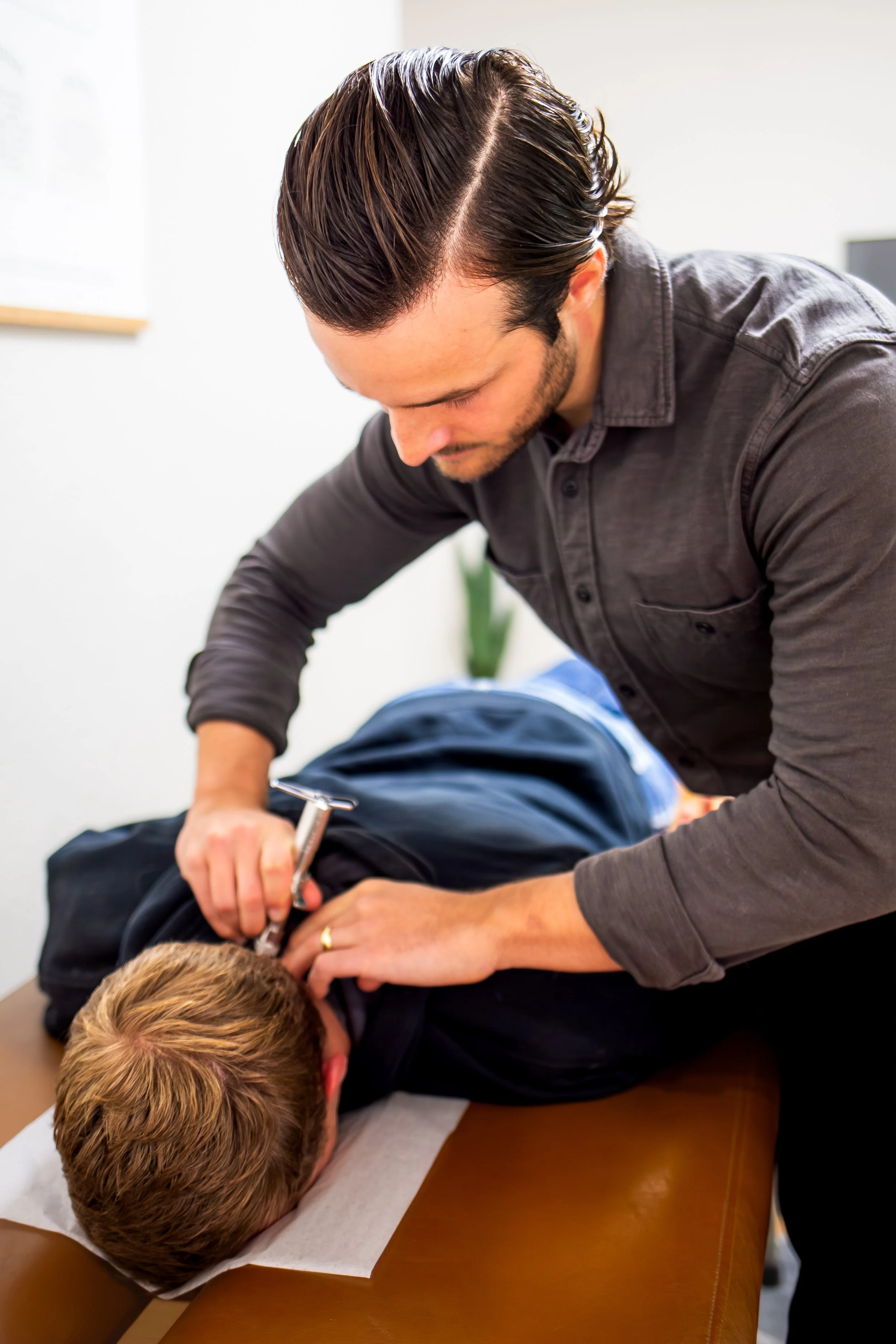 Chiropractor performing an adjustment on a patient lying face down on a chiropractic table.