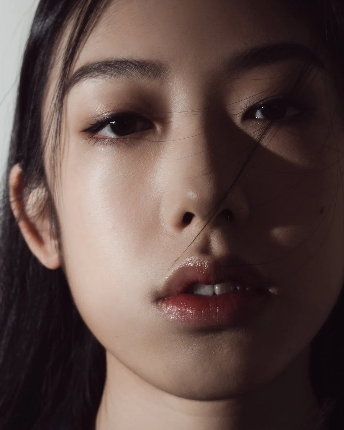Portrait of a pregnant woman with long dark hair, wearing a black crop top and black underwear against a dark background.