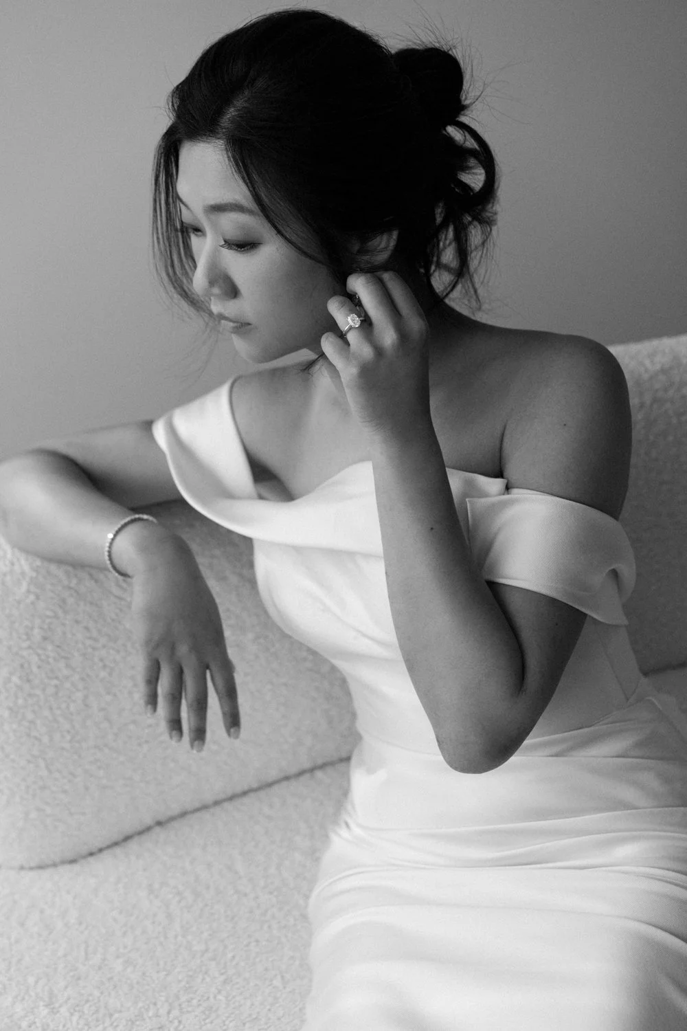 Black and white portrait of a woman wearing a veil decorated with small beads or rhinestones, looking to the right with her eyes closed.