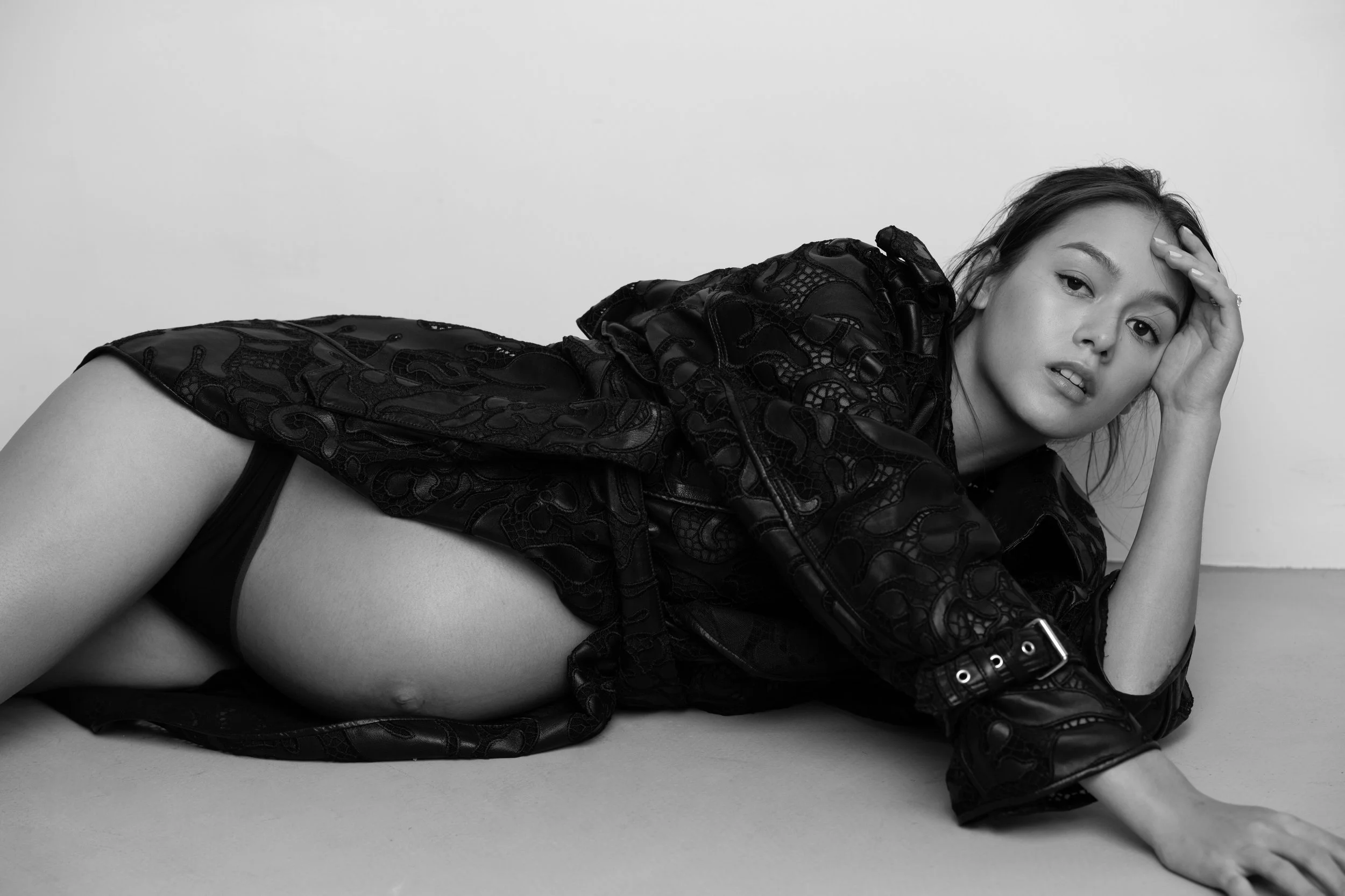 Black and white editorial maternity portrait photographed by Kay Lai Studio in Hong Kong. The mother-to-be lies down with model-like elegance, capturing an edgy and timeless artistic moment.