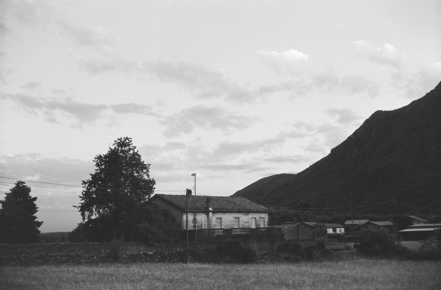 black and white farmhouse with tree and mountains