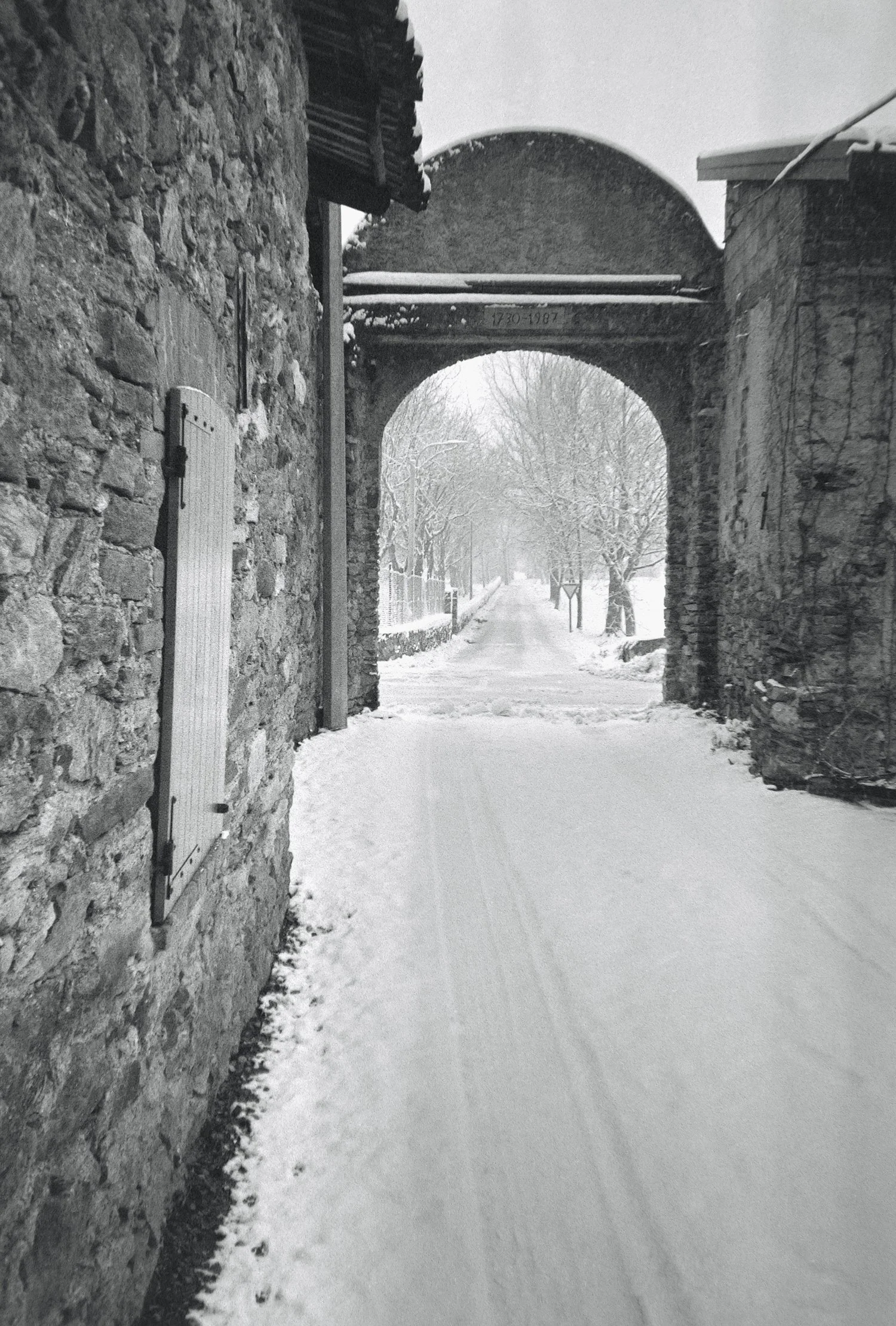 black and white stone arch at the end of a snowed-in alley