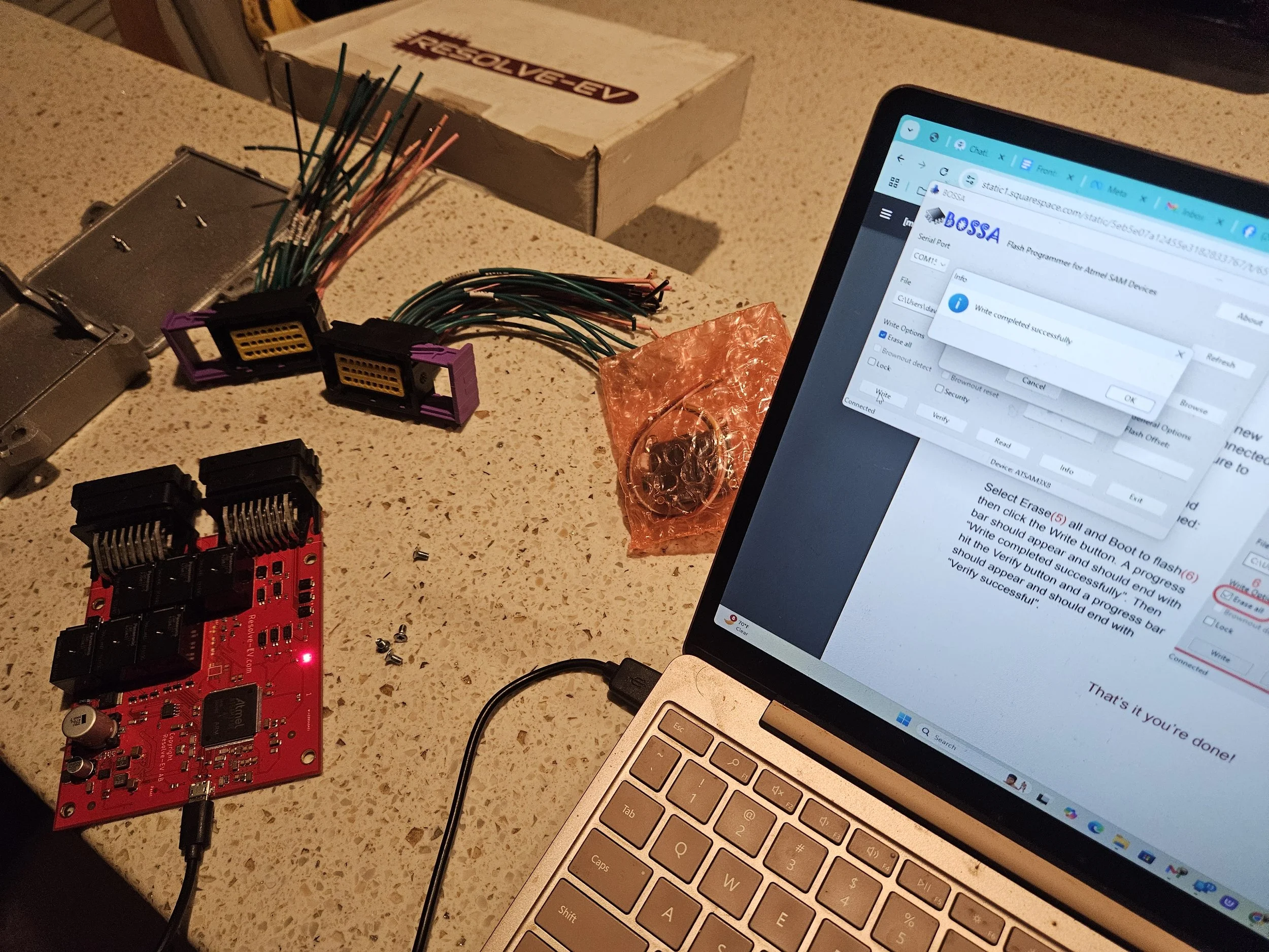 small circuit board with lit red LED plugged into laptop with window that says "Write completed succesfully"