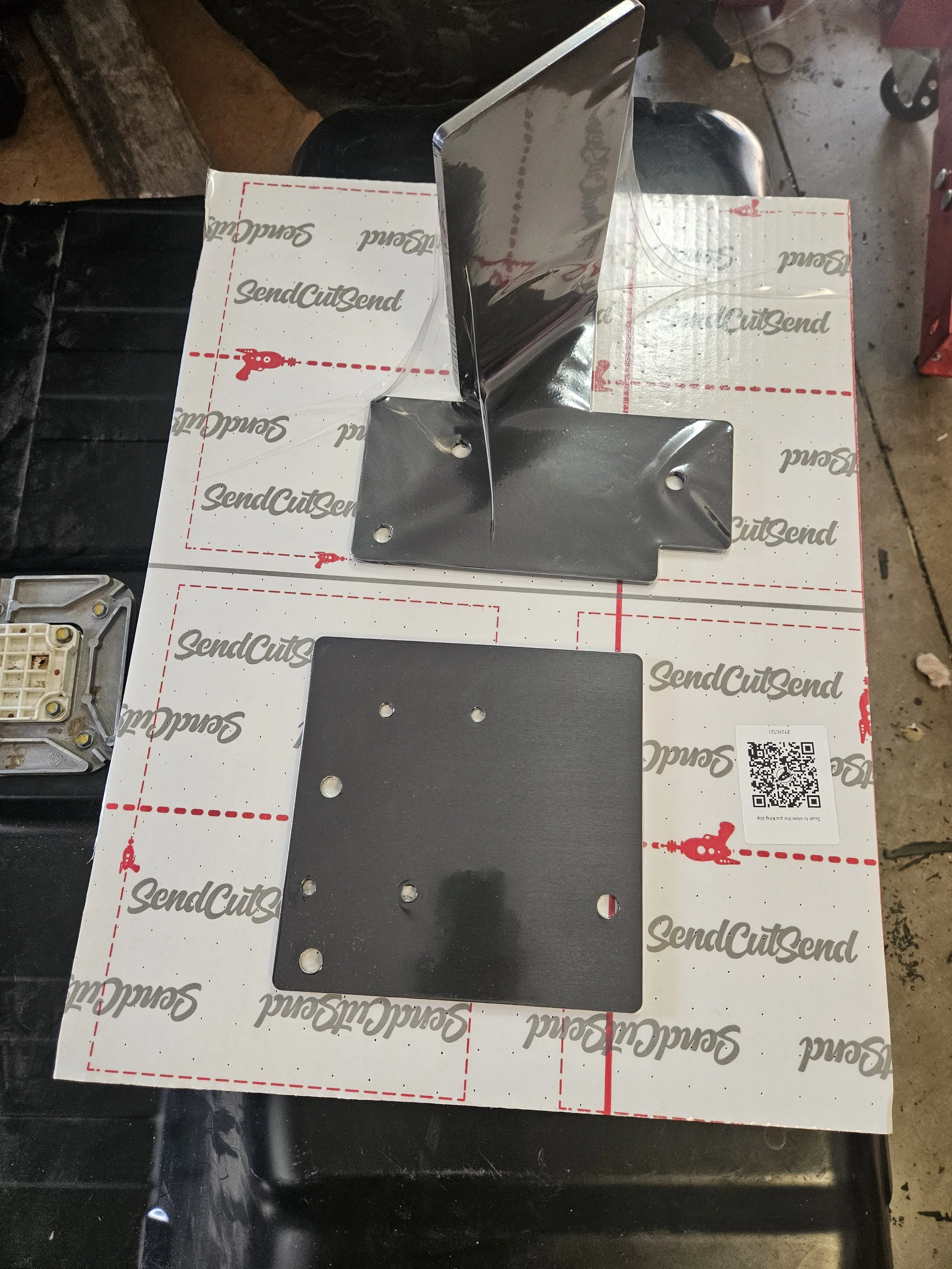 black metal pieces with holes in vacuum packaging from SendCutSend